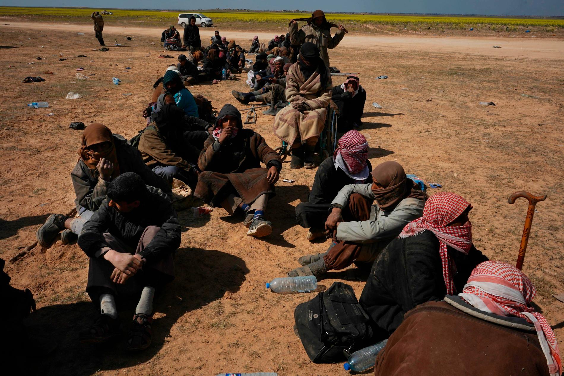 En grupp män väntar på att bli genomsökta efter att ha lämnat terrorgruppen IS sista fäste al-Baghuz i norra Syrien. Runt 800 utländska medborgare som rest till Syrien för att ansluta sig till IS befinner sig i SDF-milisens förvar.