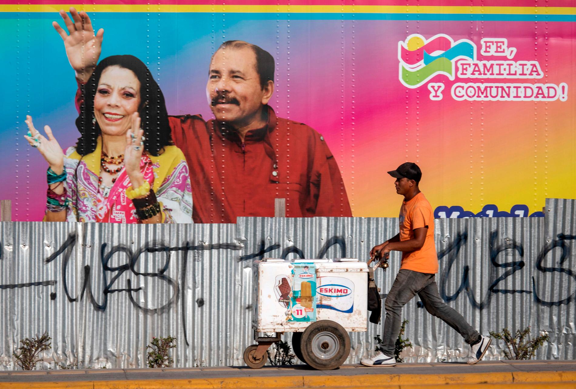 En glassförsäljare går förbi en mobil vårdinrättning med ett portträtt av Nicaraguas president Daniel Ortega och hans fru, vicepresident Rosario Murillo.