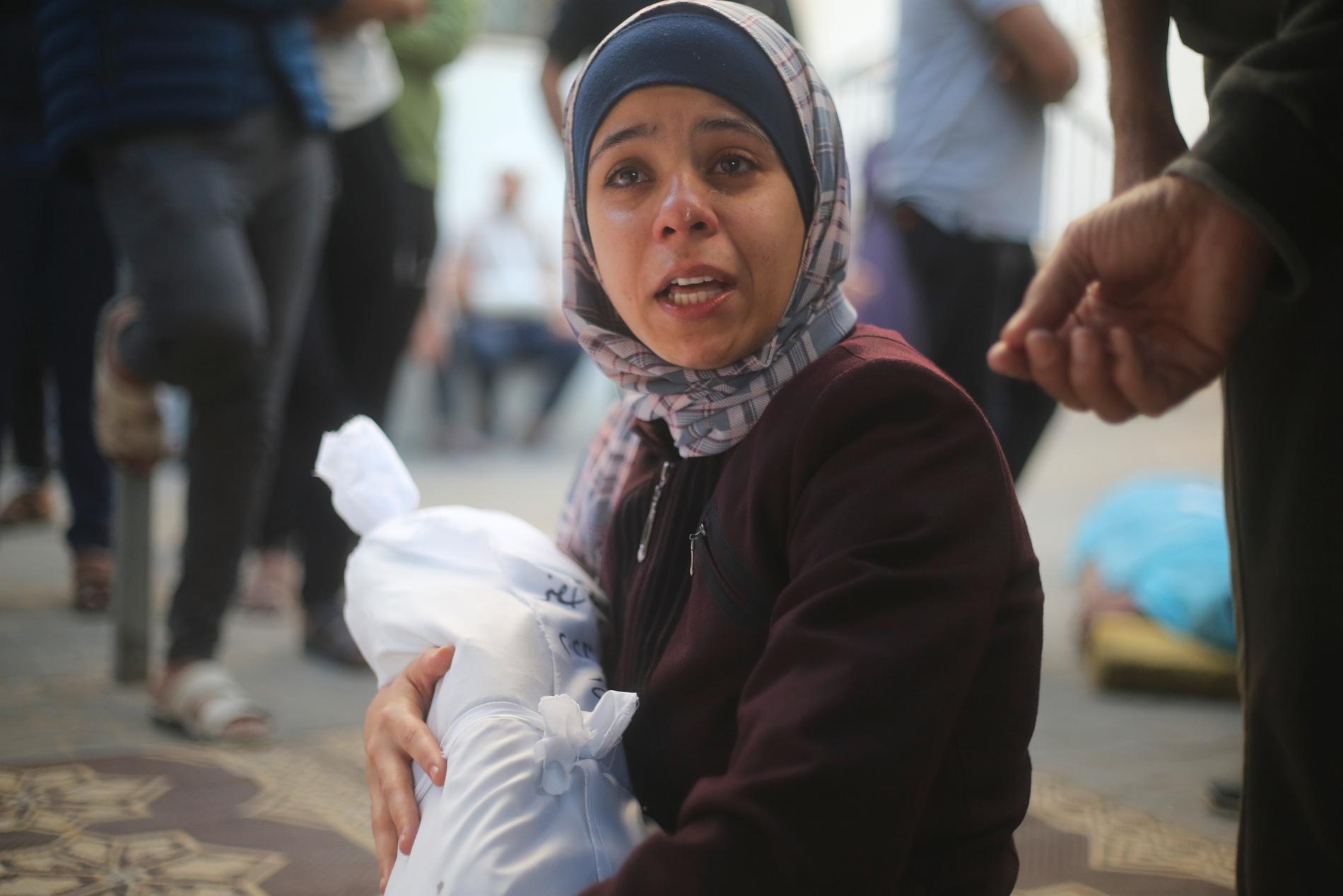 En kvinna håller i sin kusin som dödades under raketattacker inne i Gaza på lördagen.