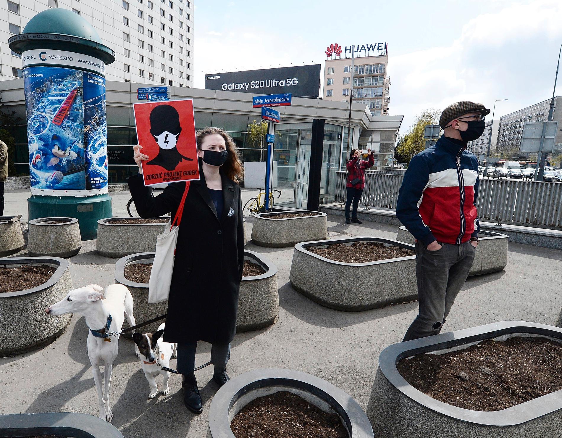 En kvinna i Warszawa protesterar mot de två nya lagförslagen som ska debatteras och röstas om i veckan under en promenad med sina hundar.