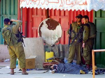 Israeliska soldater fotograferas vid en död palestinier.