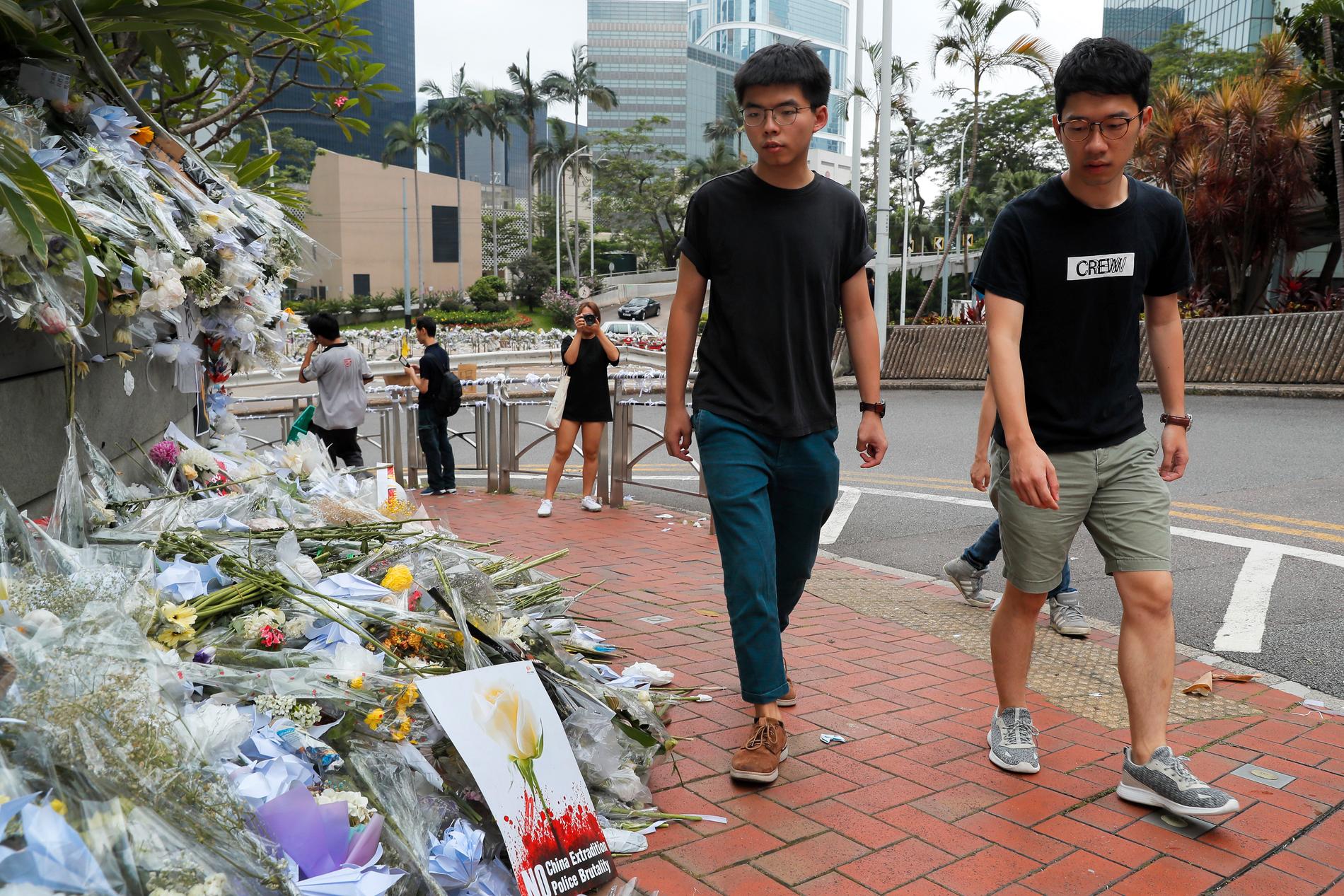 Aktivisten Joshua Wong (till vänster) besöker minnesplatsen för en aktivist som dog efter att ha fallit ned från en byggnad där han satte upp en banderoll.