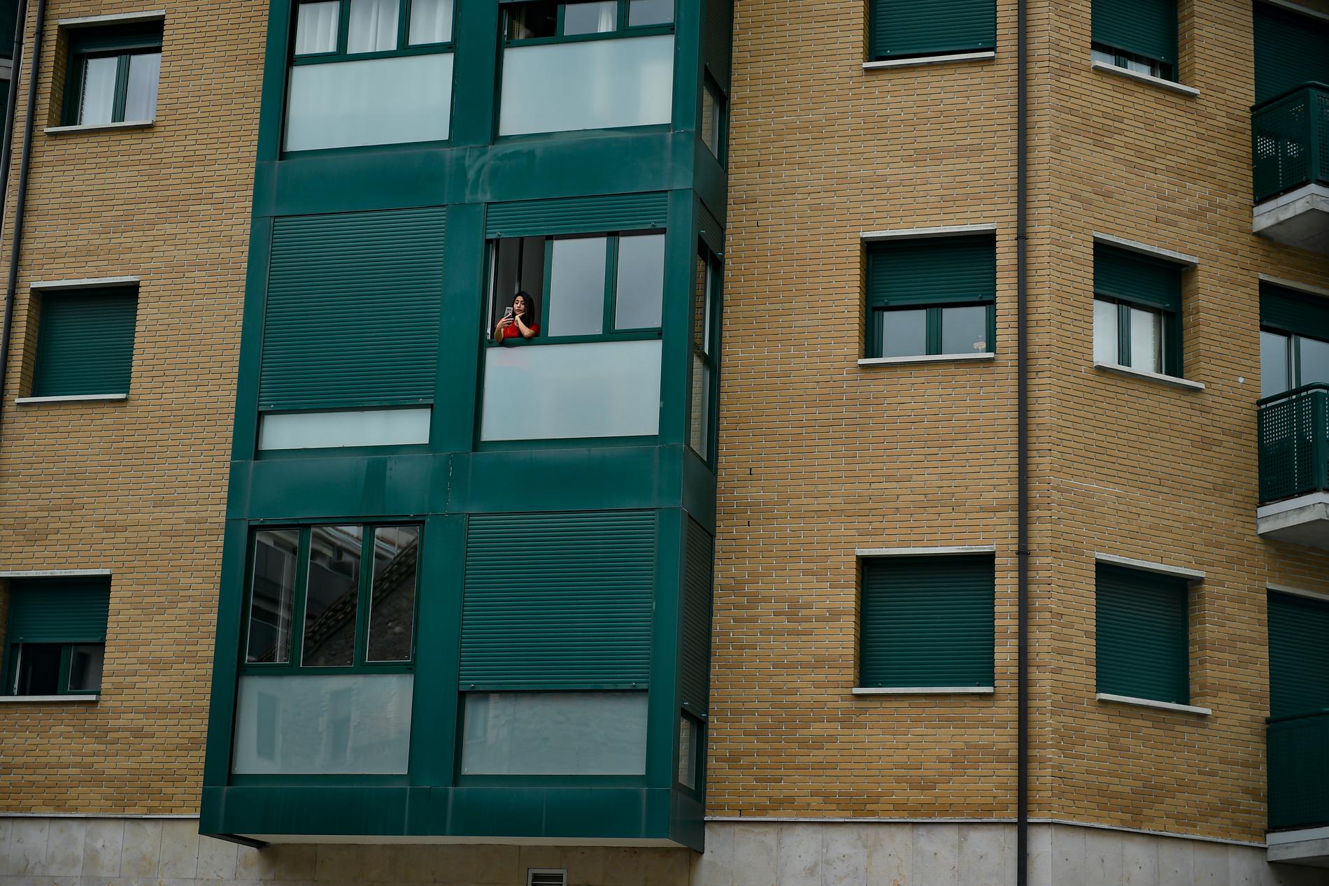 En kvinna tar en bild från fönstret i Villava i Spanien.