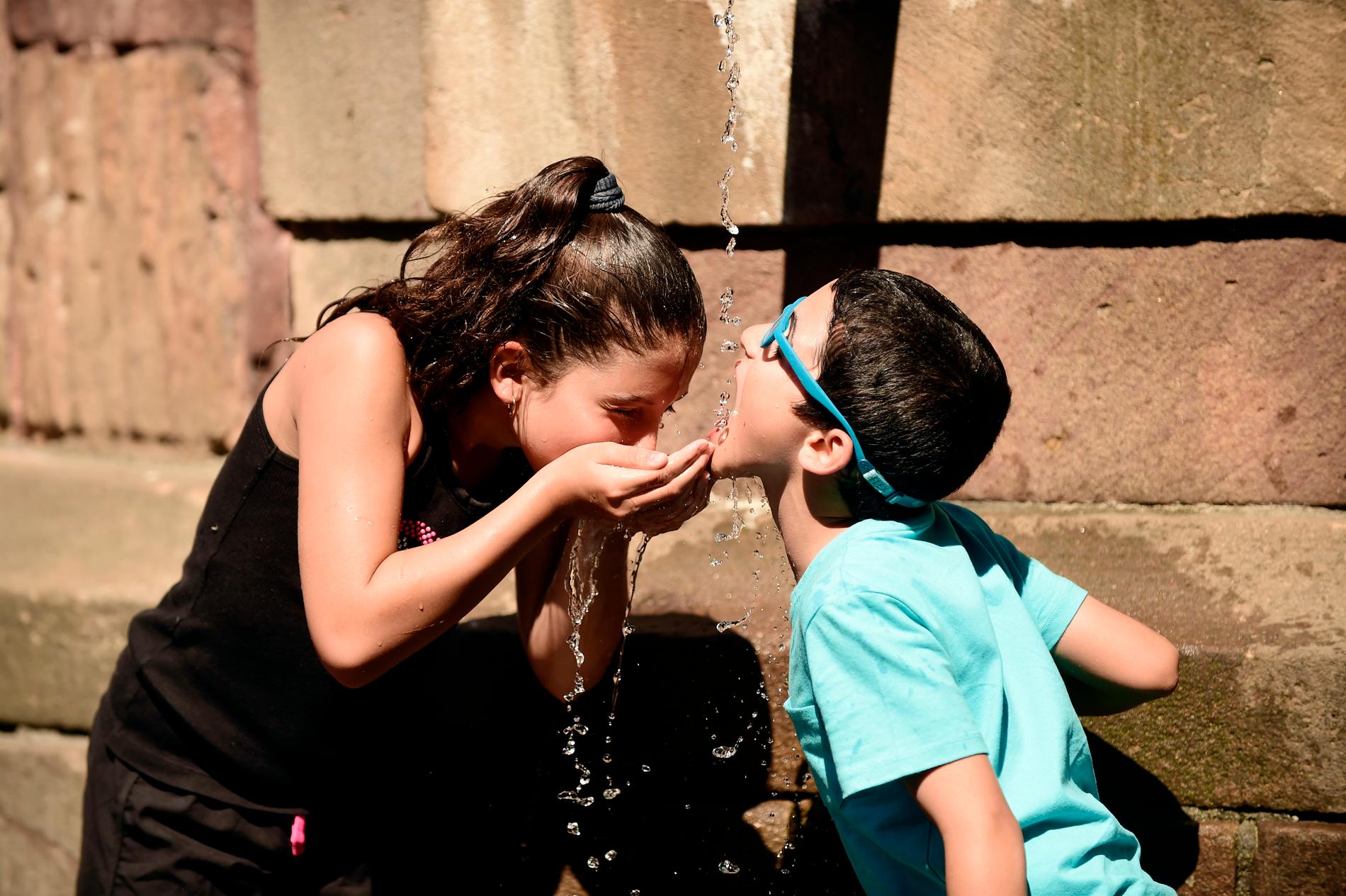 Arkivbild. Två barn dricker vatten ur en fontän i Gamla stan i Stockholm.