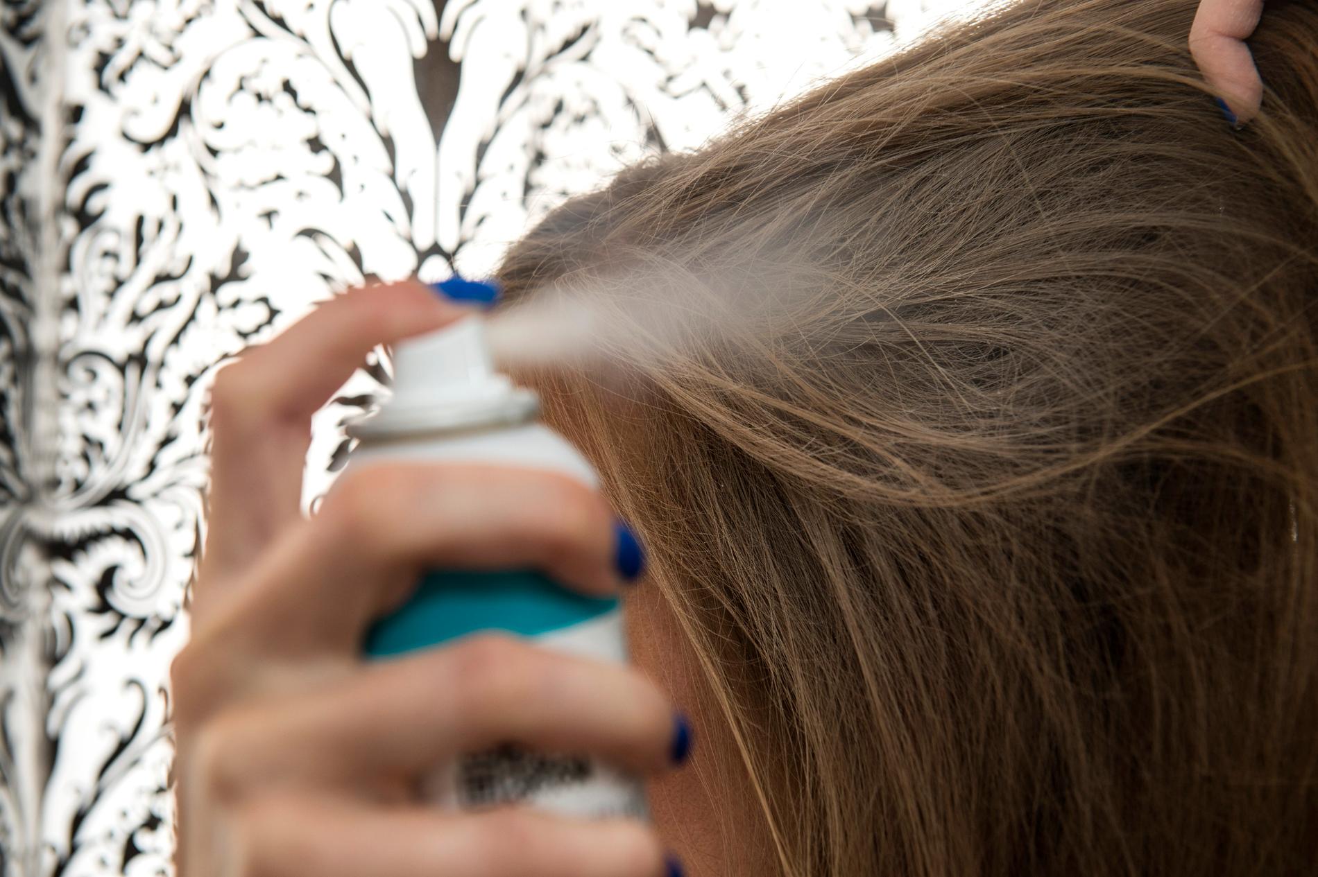 En person tar torrschampo i håret.