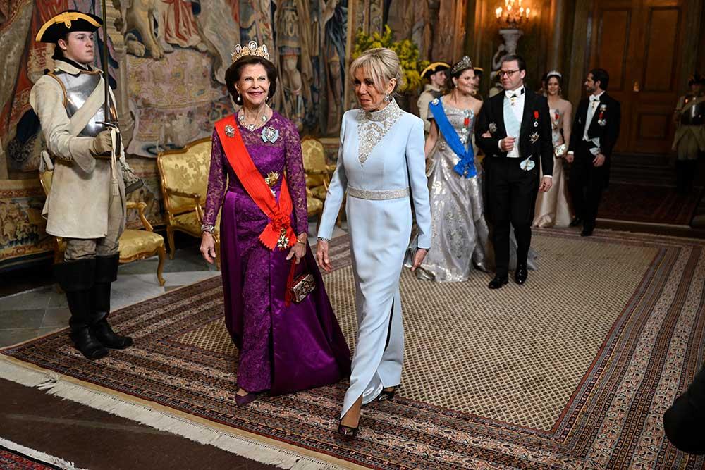 Drottning Silvia och Frankrikes presidentfru Brigitte Macron. Drottningens mörklila klänning i brodyrspets och duchesse är ett återbruk, hon bar den även vid Nobelfestligheterna 2022. Hon bär det vackra kamégarnityret som består av ett diadem med tillhörande örhängen, halsband och armband. 