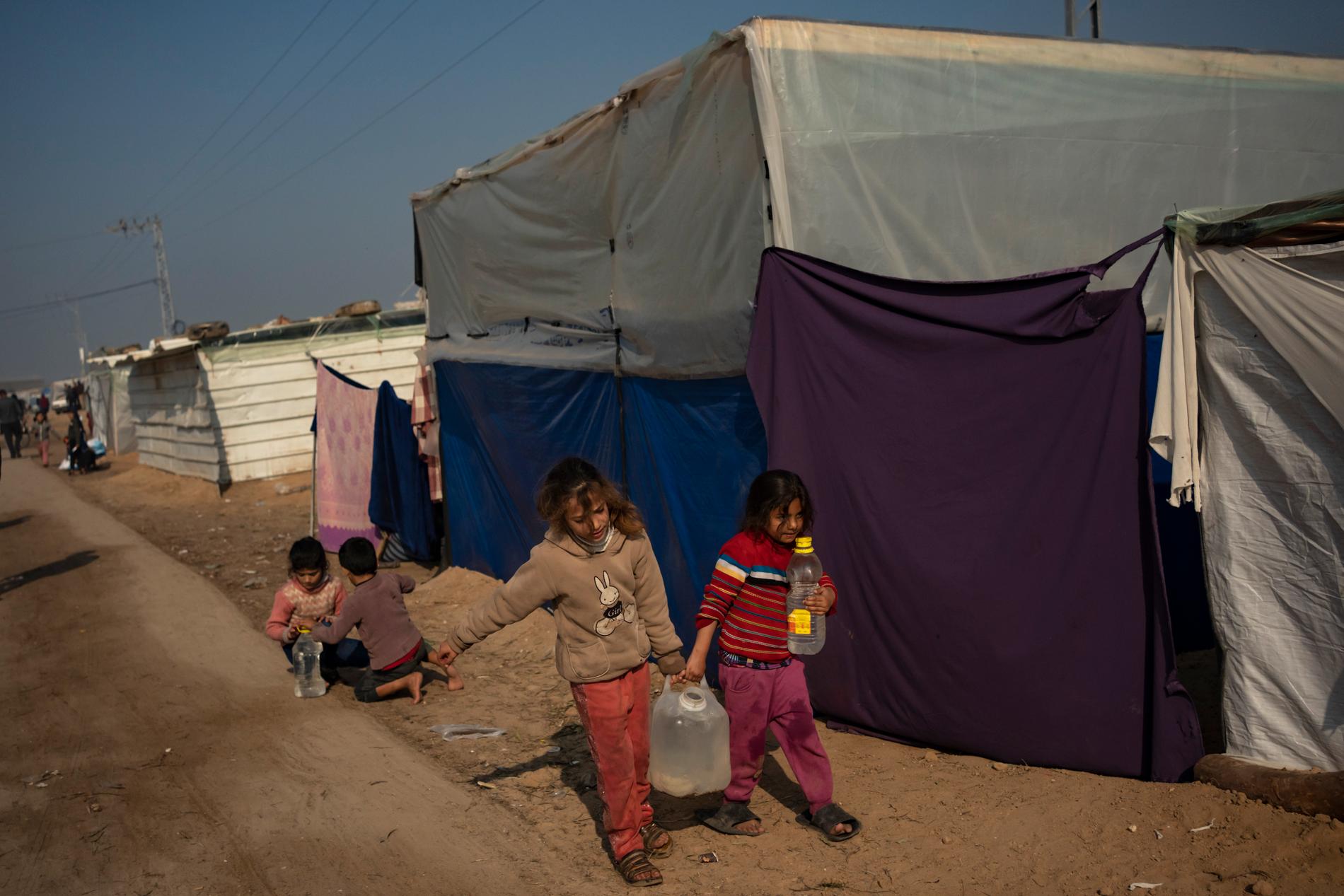 Palestinska barn hämtar vatten i ett provisoriskt tältläger i Mawasi i Gaza den 18 december.