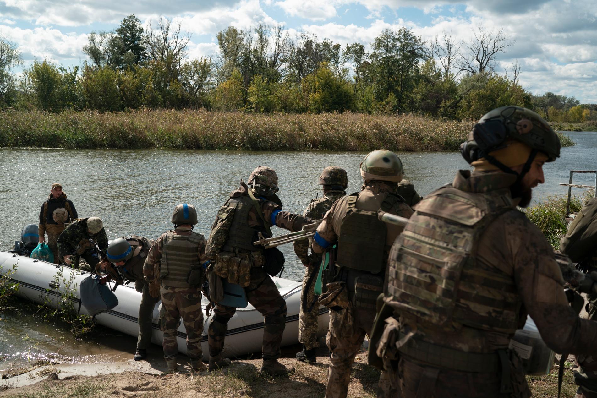 Ukrainska soldater tar sig upp på flodbanken vid Dnepr.