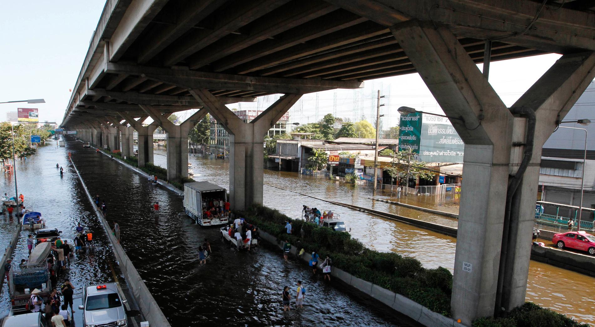 Bilar på en översvämmad väg i Bangkok.