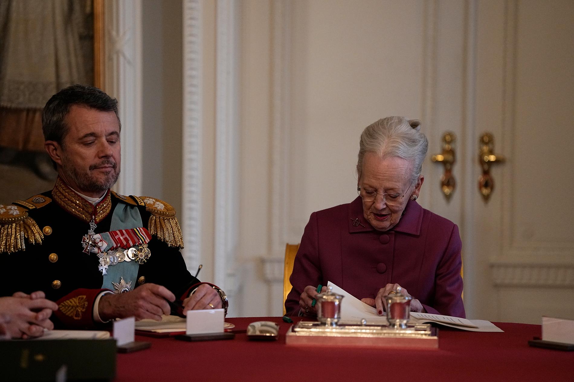 Drottningen undertecknar sin abdikation. Vid sin sida har hon sin son och Danmarks nya kung Frederik X. 