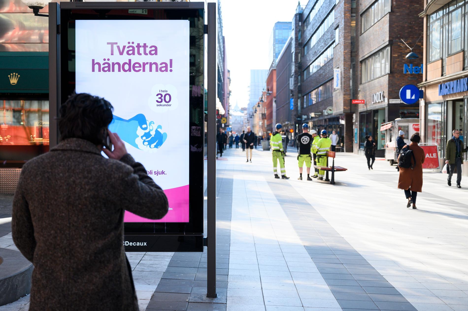 Informationsskylt på Drottninggatan i Stockholm som uppmanar folk att tvätta händerna. Arkivbild.