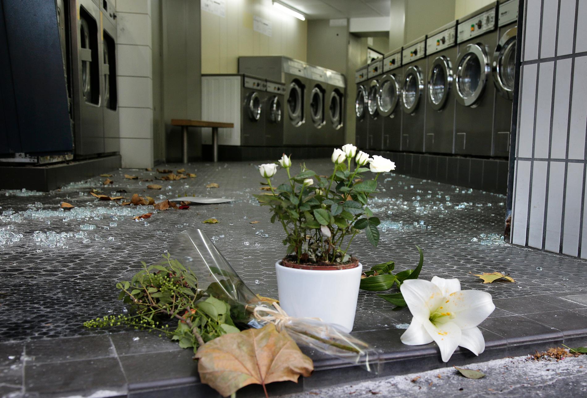 Blommor och glassplitter kantar en tvättinrättning i närheten av en av platserna för attackerna.