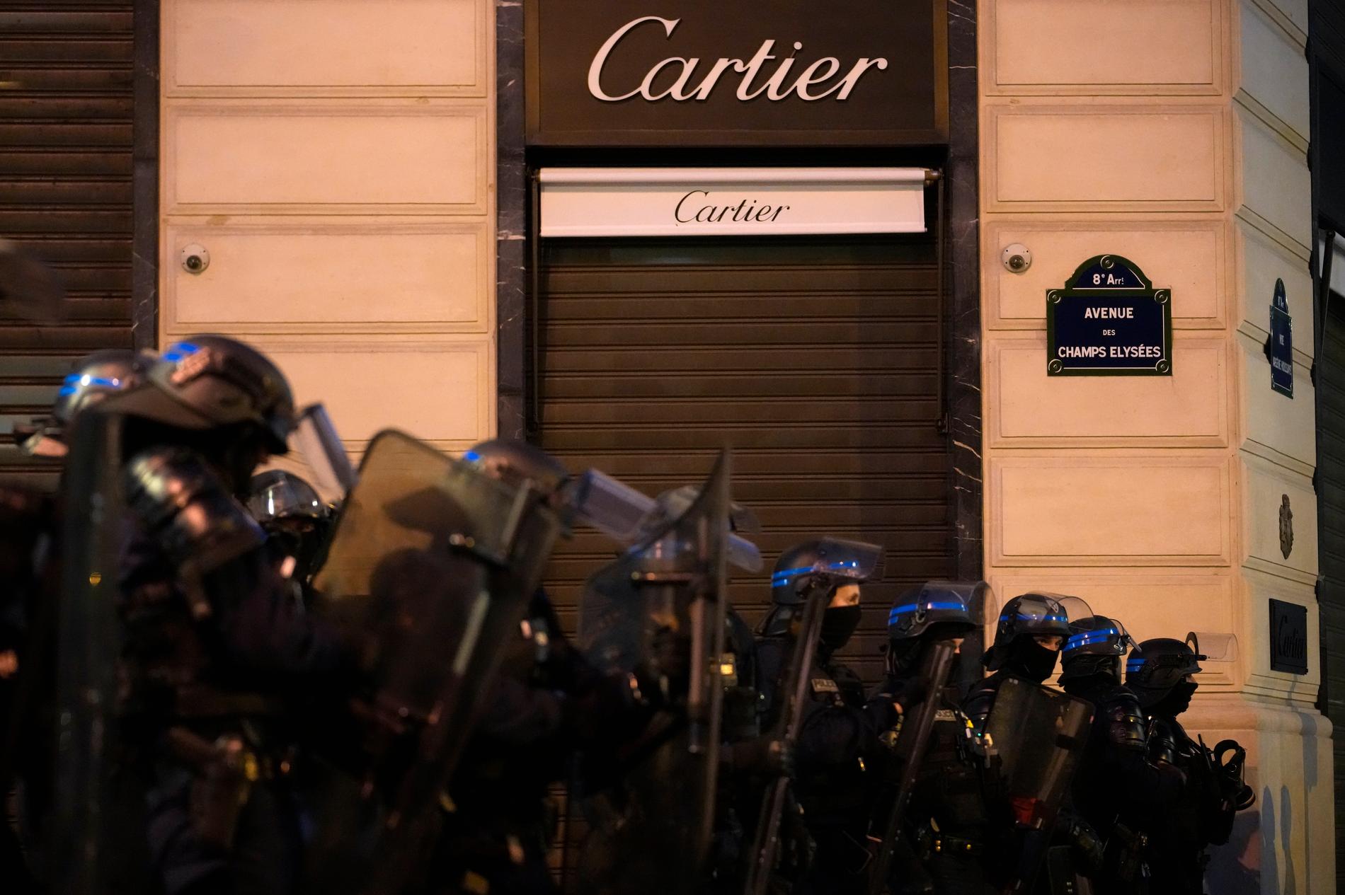 Kravallpoliser står uppradade längs paradgatan Champs Elysees i Paris på lördagskvällen.