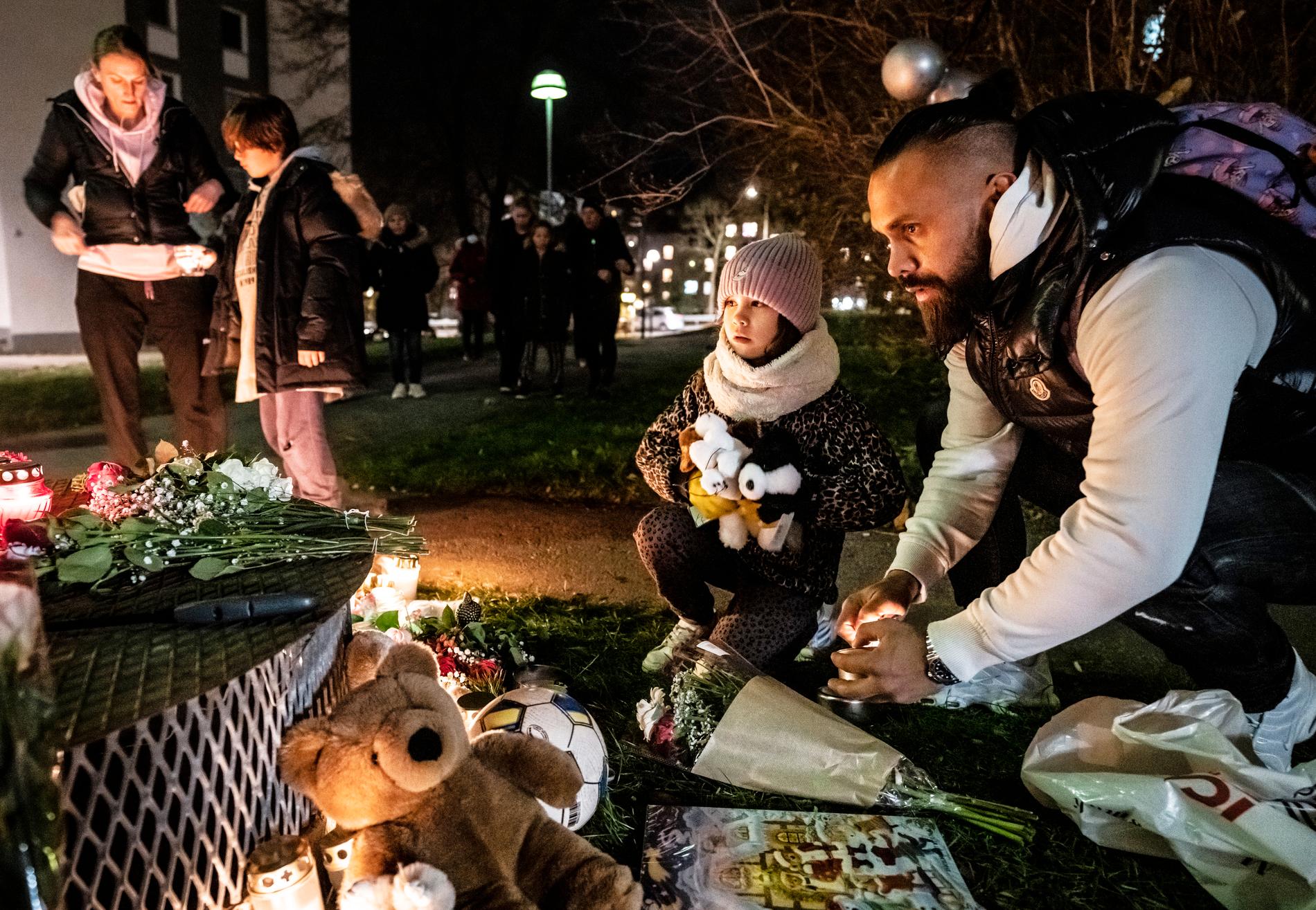 Pappa Patrick Nielsen och dottern Jocelin har kommit för att tända ljus och lägga två gosedjur på minnesplatsen i Hässelby Strand.