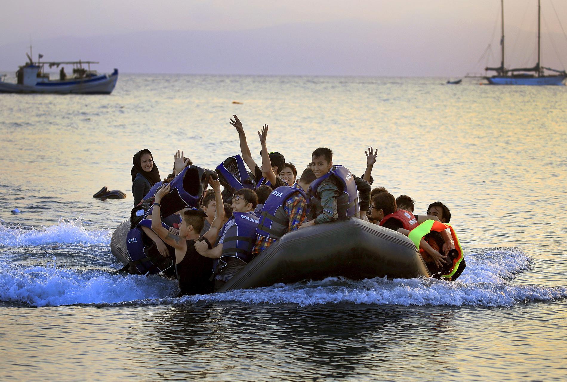 Flyktingar från Afghanistan jublar när de anländer till stranden på ön Kos.