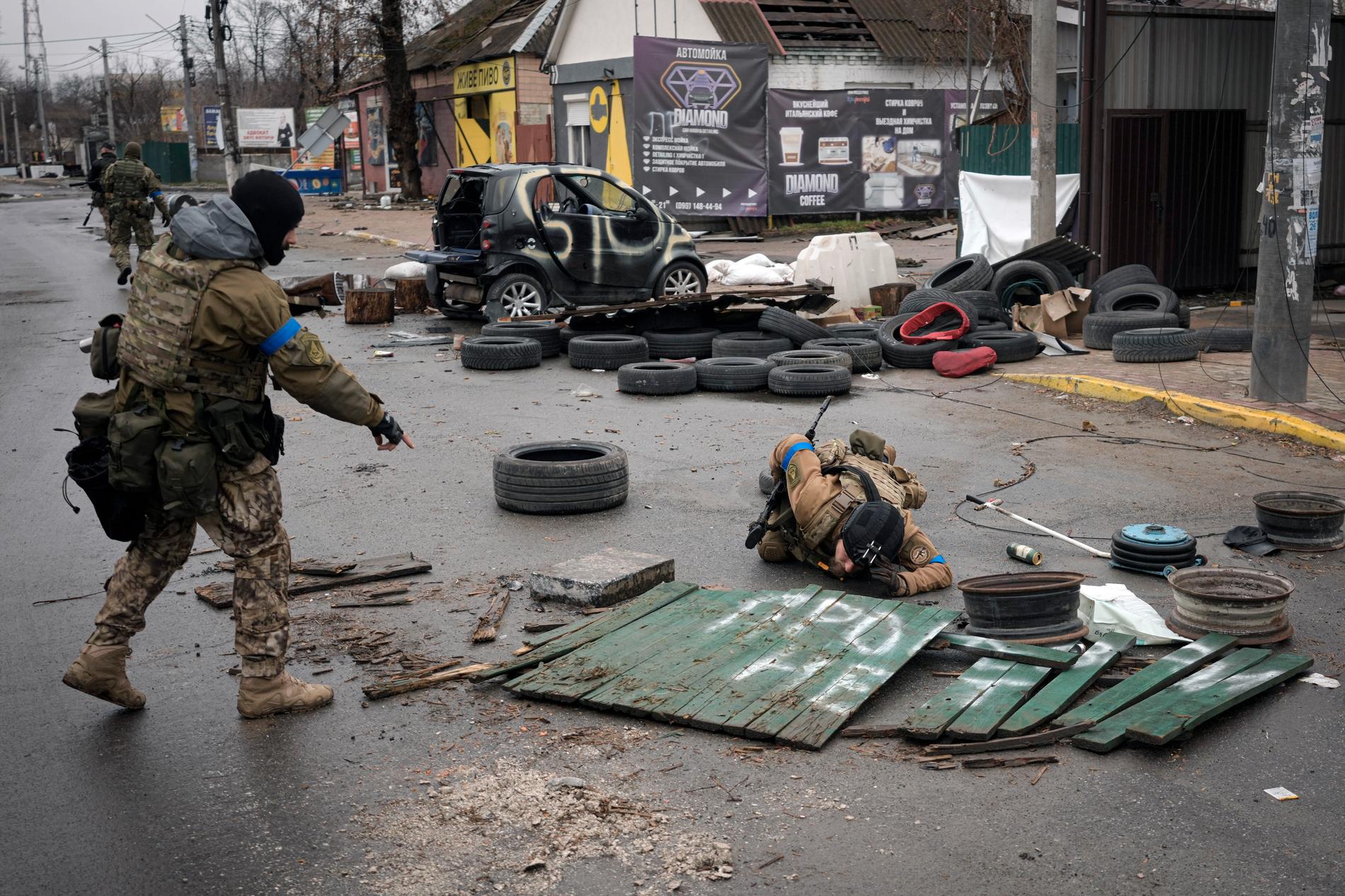 Ukrainska soldater tittar efter fällor lämnade av ryssarna på Butjas gator. President Zelenskyj varnade under natten för att ryska styrkor kan ha minerat döda kroppar och annat i de tidigare ockuperade områdena.