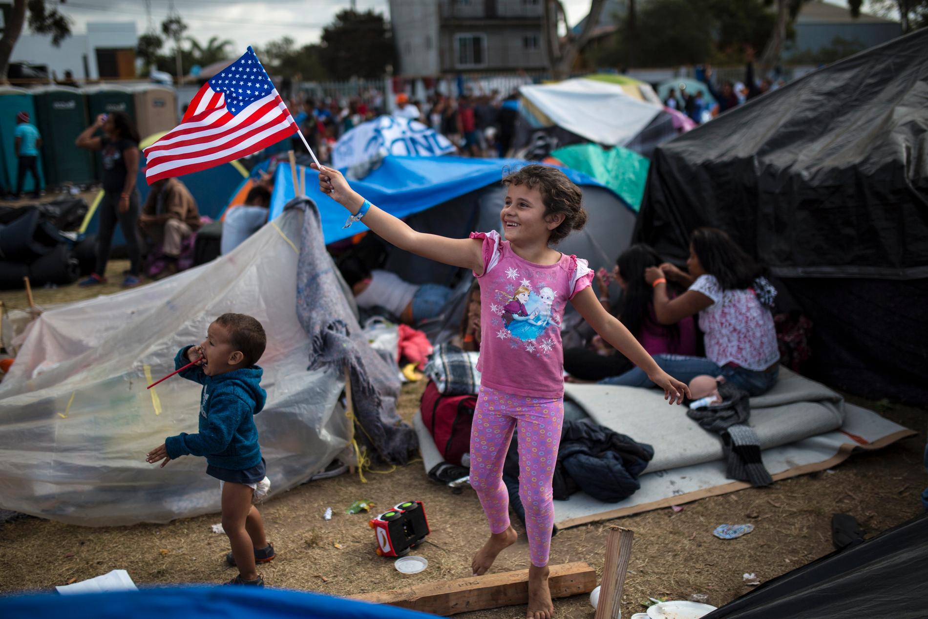 En sjuåring från Honduras viftar med USA:s flagga i ett läger för centralamerikanska migranter i Tijuana, Mexiko.
