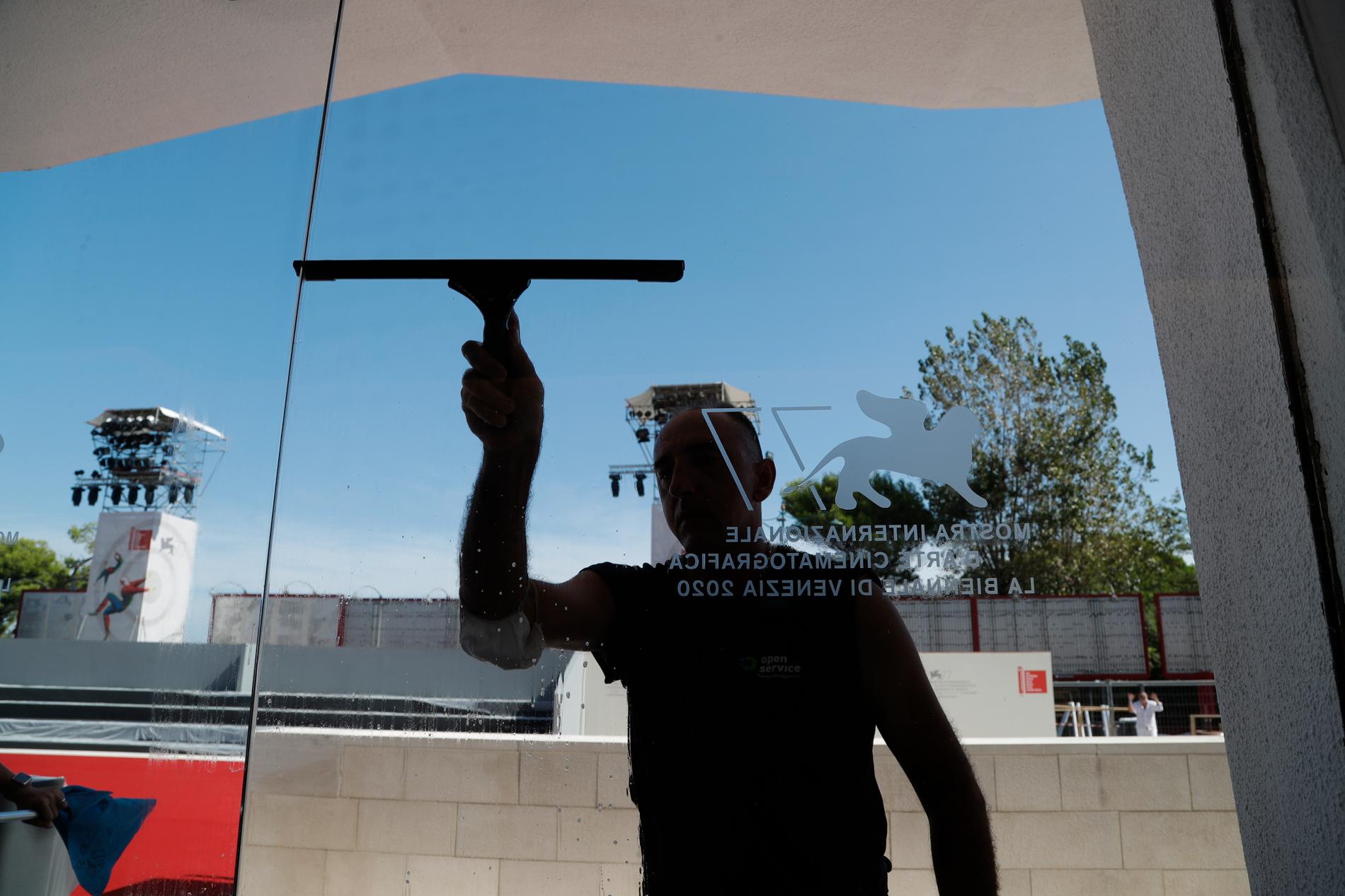 En fönsterputsare gör rent glasdörren till Palazzo del Cinema på Lido i Venedig inför invigningsceremonin av filmfestivalen den 2 september.