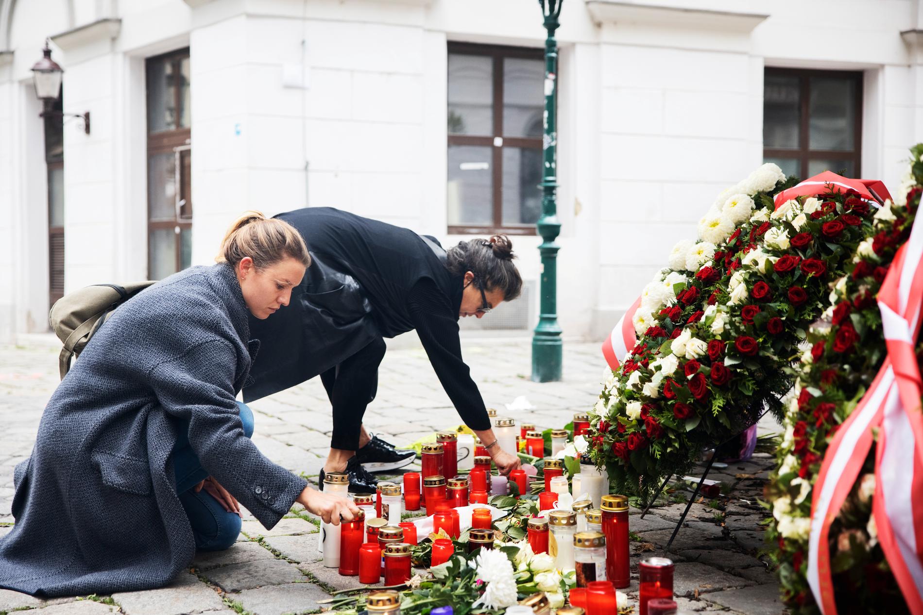 Två kvinnor tänder ljus på Dieter-Freidman Platz i Wien där terrorattacken ägde rum.