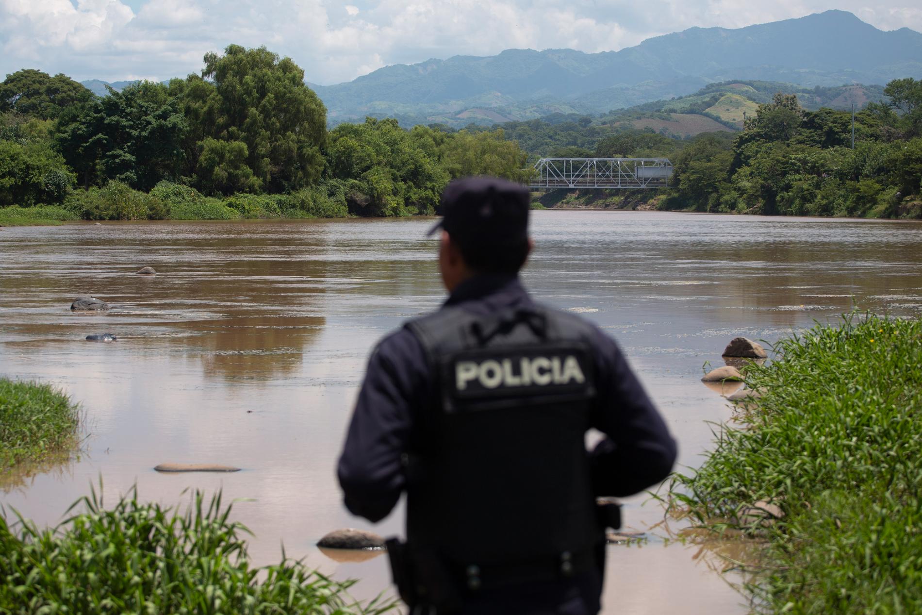 En polis i El Salvador ser ut över en flod vid gränsen mot Guatemala. Arkivbild.