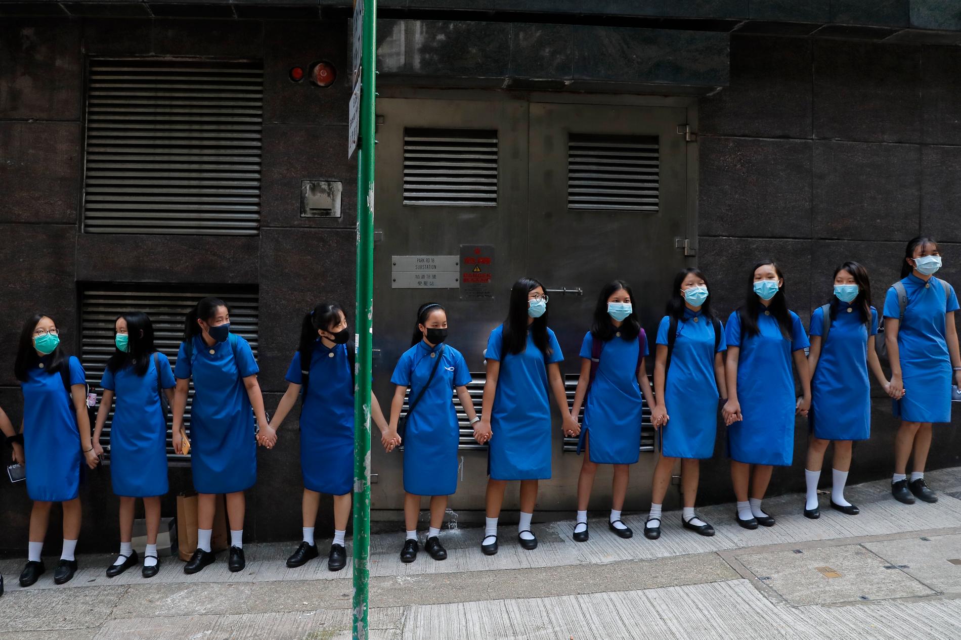 Maskerade studenter håller varandra i händerna vid S:t Stephens Girls' College i Hongkong.