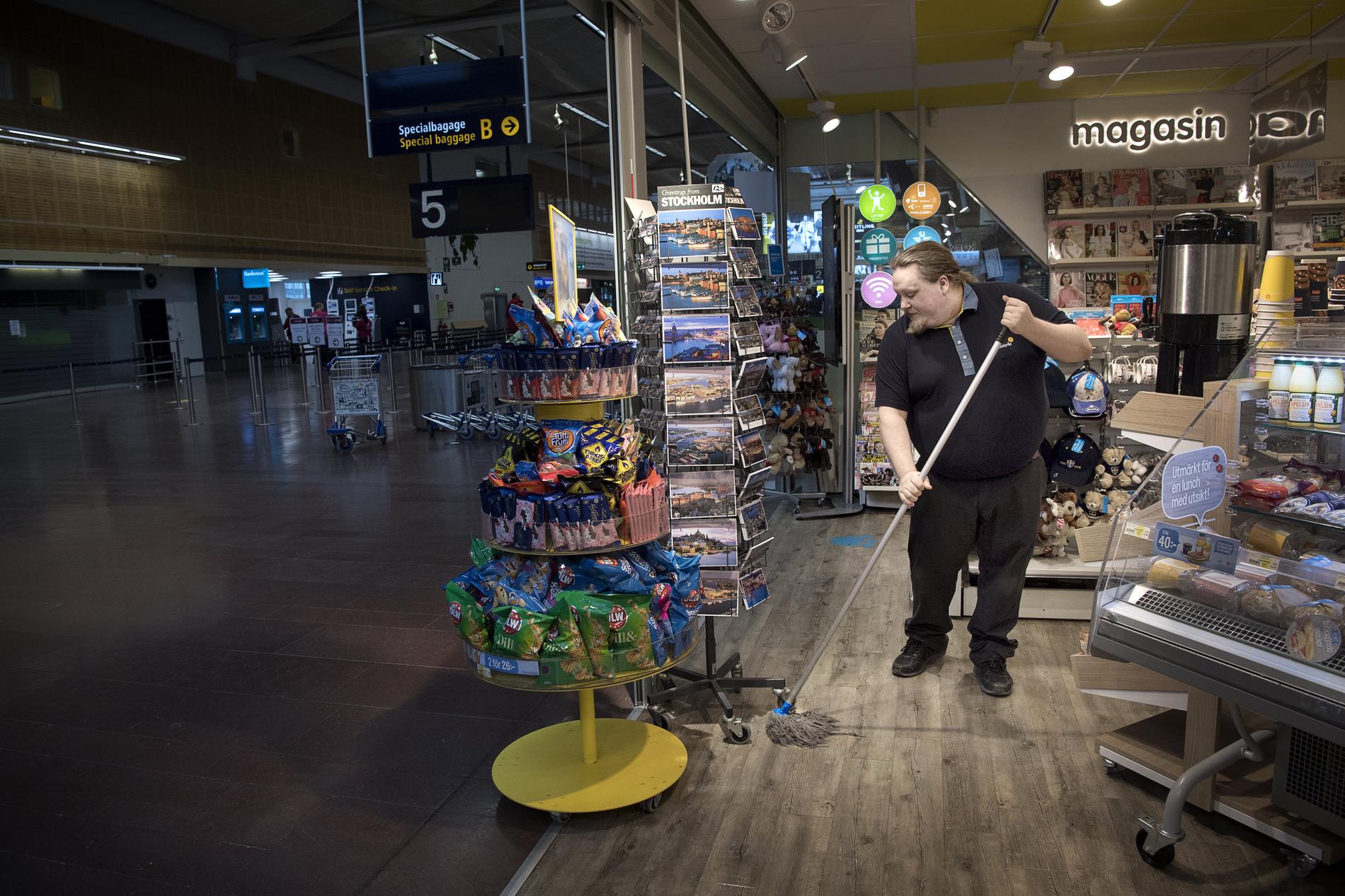 Mattias Byberg, anställd på pressbyrån i Terminal 5 på Arlanda, passar på att städa när det inte finns några kunder.