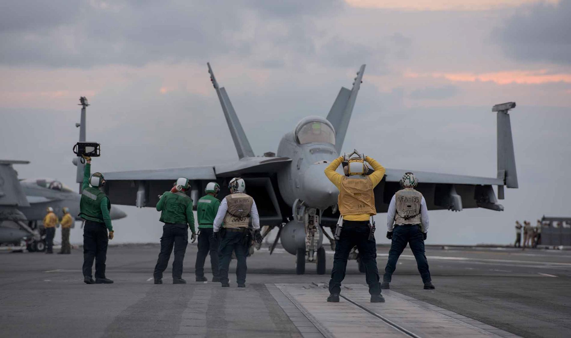 Sjömännen förbereder för att ett stridsflygplan av typen F/A-18 ska lyfta.