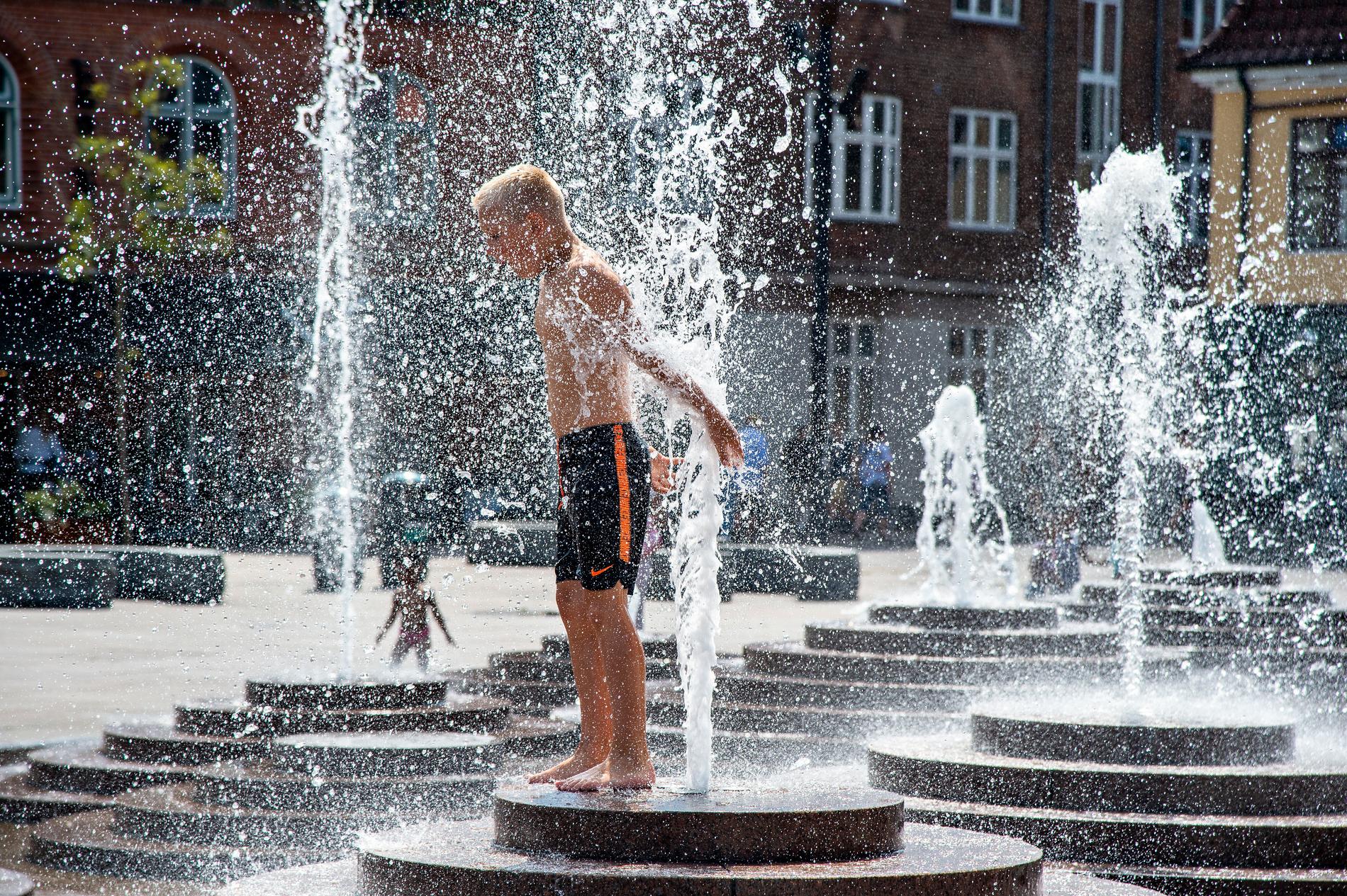 En pojke tar en kalldusch på Toldbod Plads i danska Ålborg. 