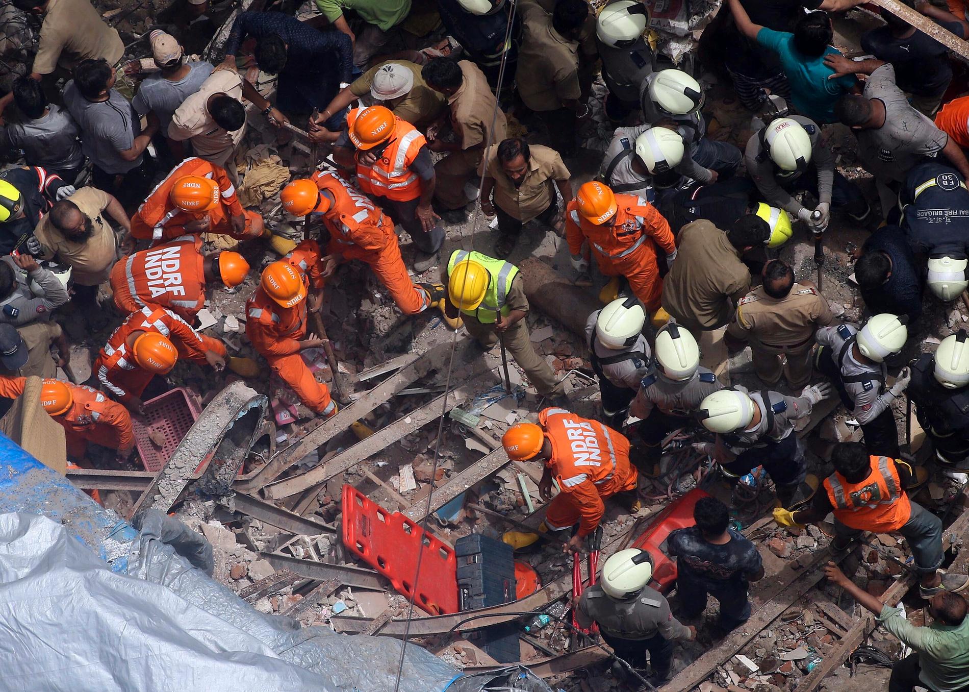 Räddningsarbetare vid det rasade huset i Bombay.