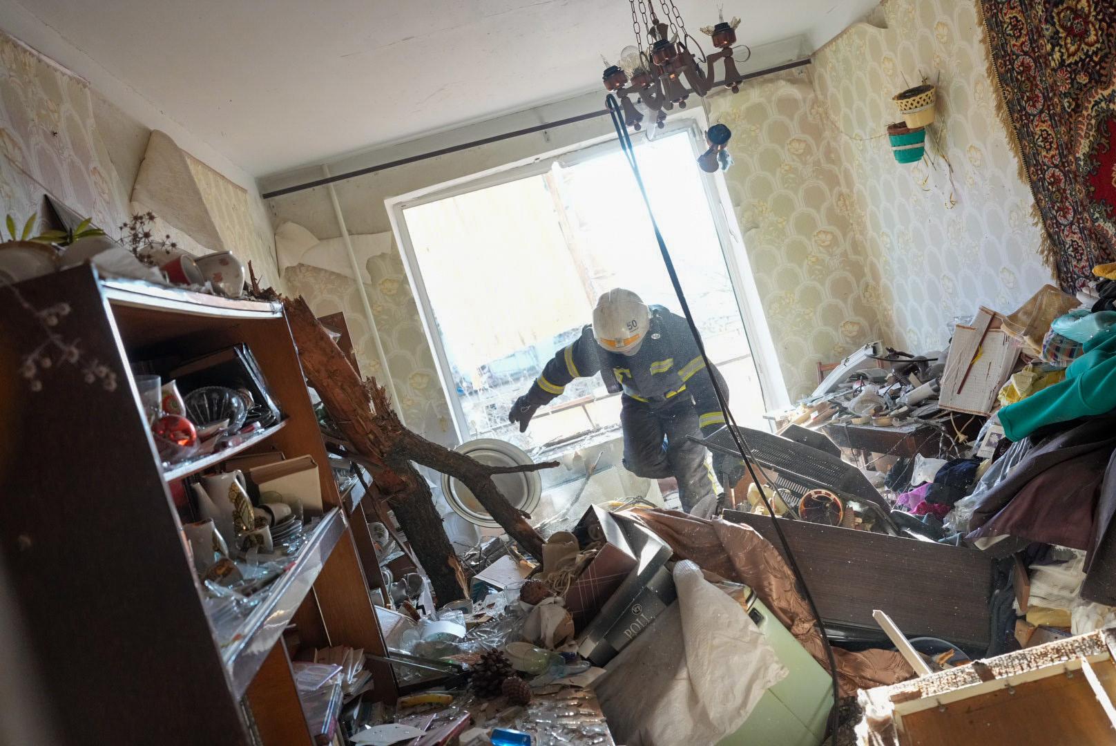 En brandman tar sig in i en förstörd lägenhet i Charkiv.