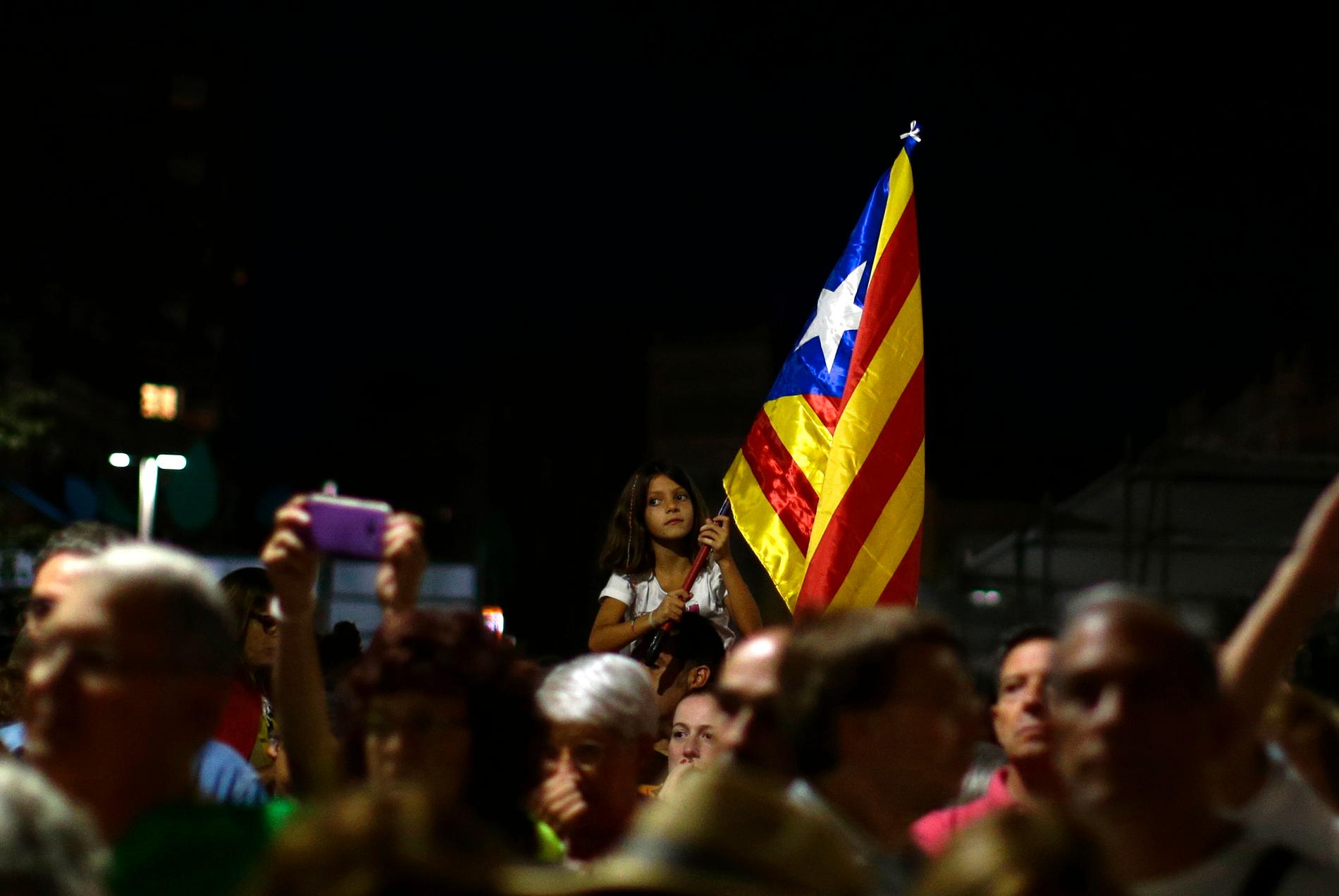 En flicka håller den katalanska flaggan inför dagens massdemonstrationer i Barcelona.