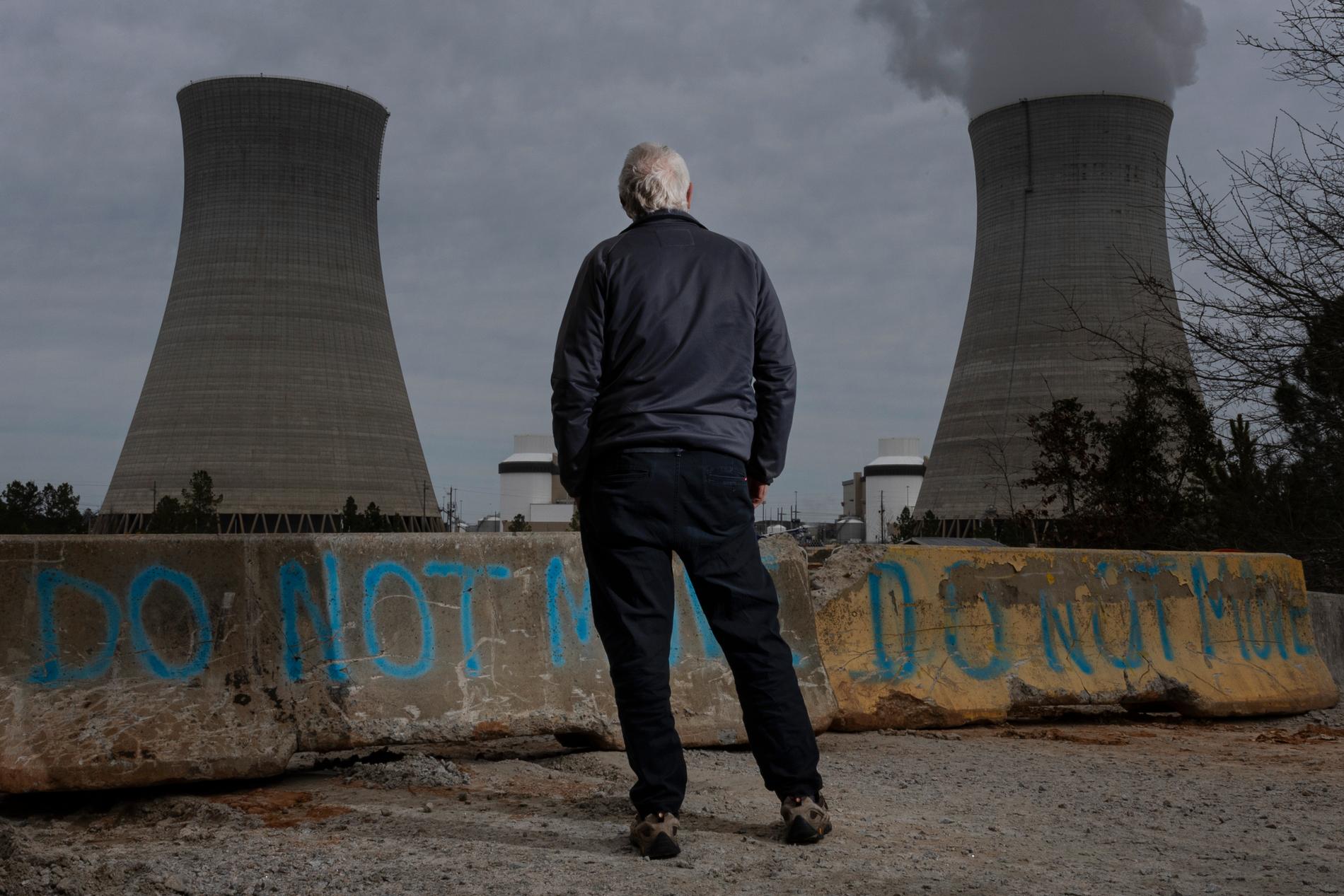 Tom Clements från miljöorganisationen Jordens Vänner står med ryggen mot kameran. I bakgrunden ser man kärnkraftverk.