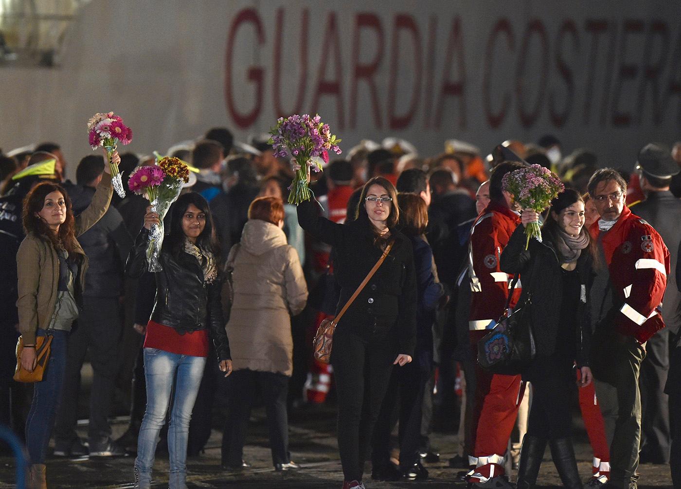 Människorättsaktivister håller blommor i hamnen.