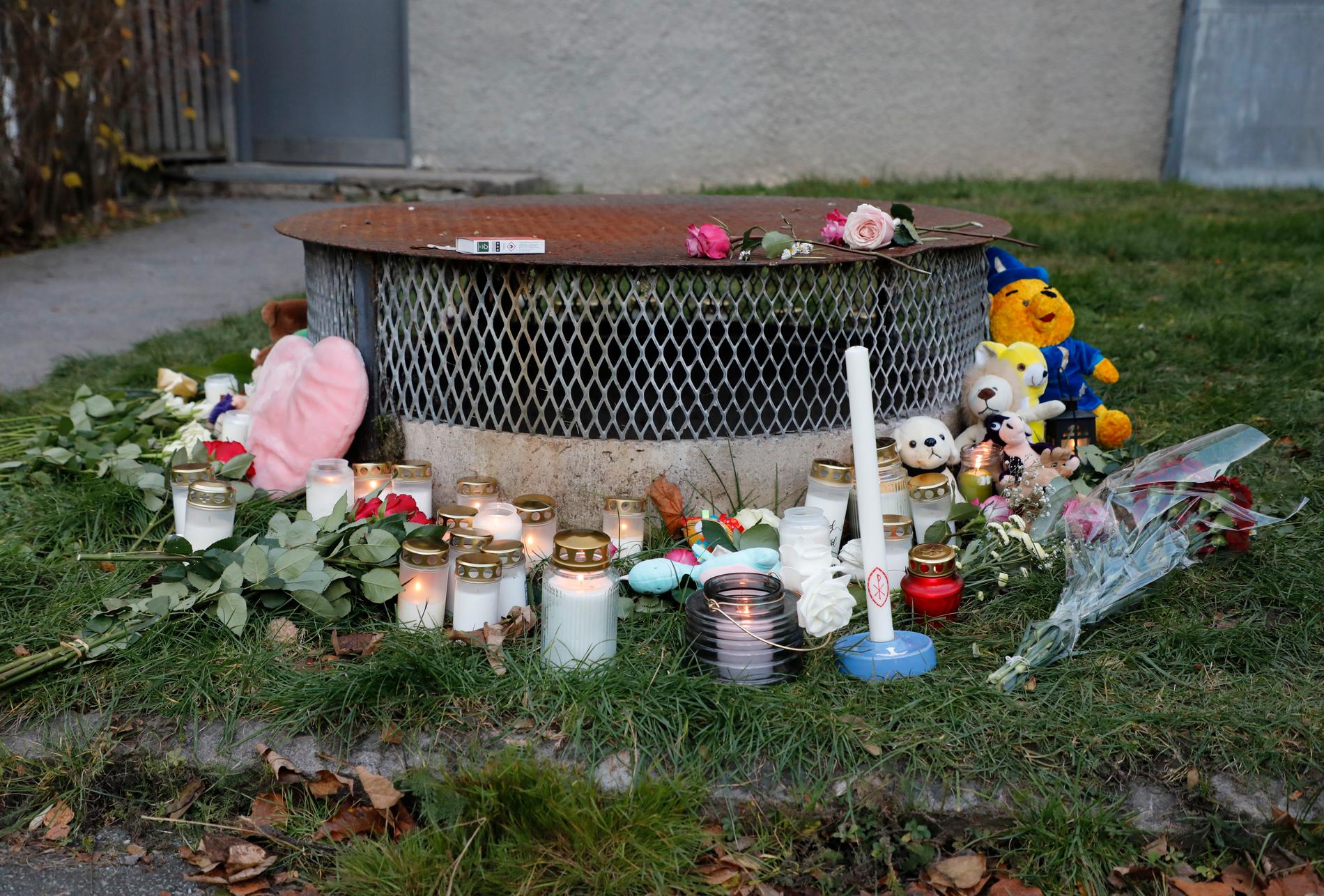 Gosedjur, blommor och ljus vid den plats där två barn hittades med livshotande skador utanför ett bostadshus i Hässelby i höstas. Ett av barnen avled av sina skador. Arkivbild.