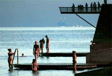 TROPISK NATT I SVERIGE I Västra hamnen i samlades många Malmöbor för att ta ett svalkande bad i den tropiska natten. I bakgrunden dallrar kärnkraftverket i Barsebäck i hettan.