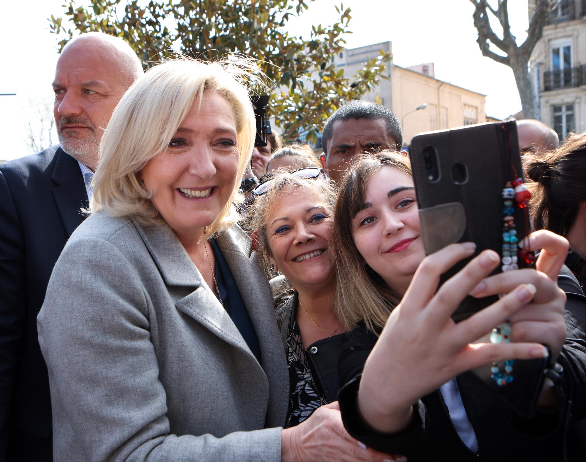Marine Le Pen ställer upp på selfies med några unga fans. 