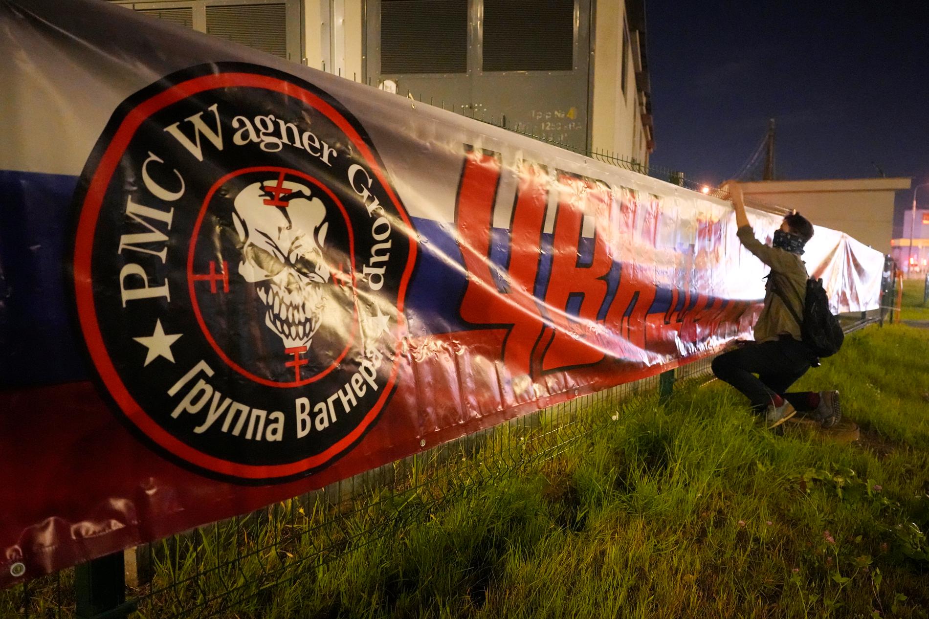 En man hänger upp en banner med texten ”Wagnergruppen – vi är tillsammans”