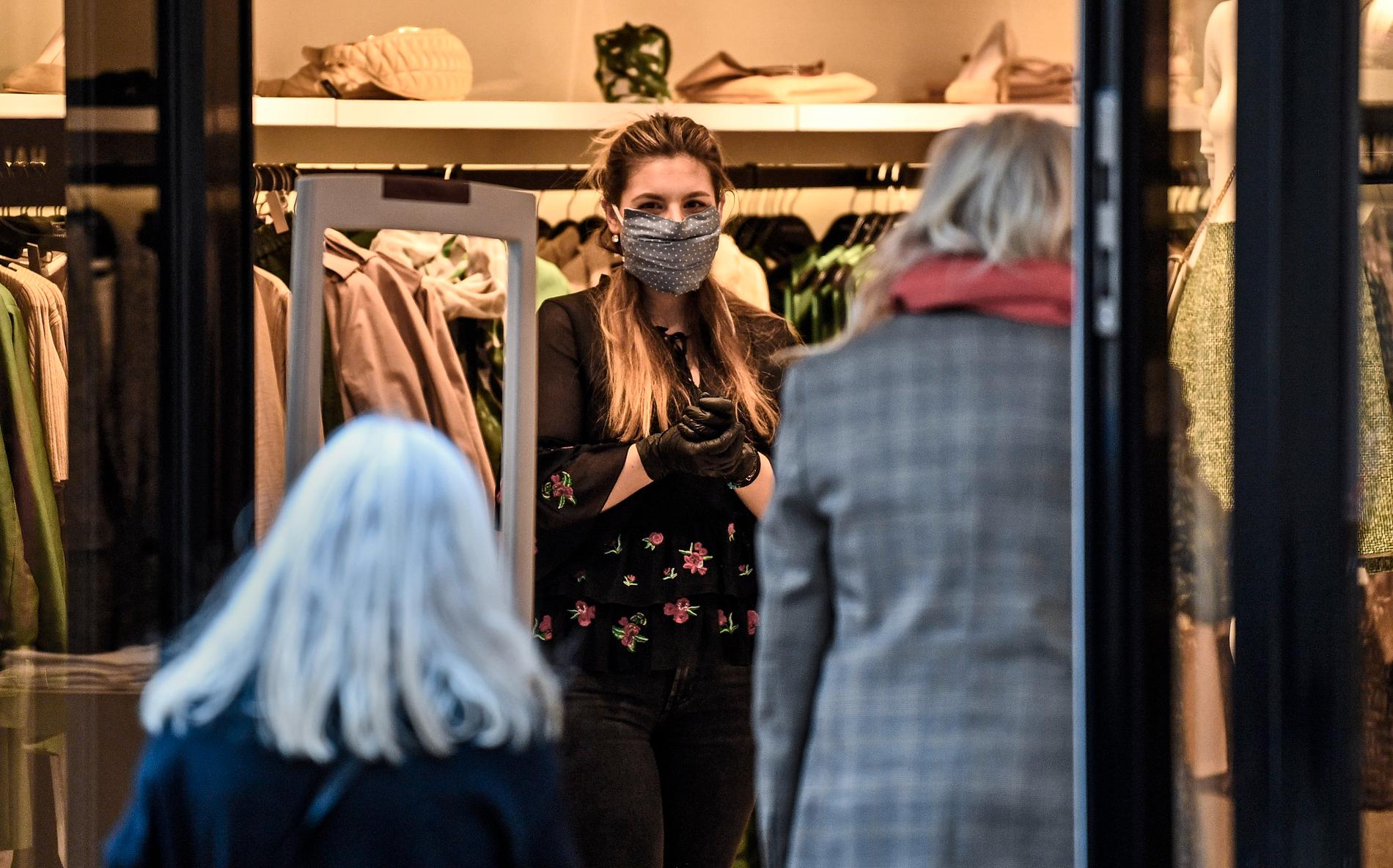 En butiksanställd tar emot en kund i en mindre butik i Essen i västra Tyskland den 20 april. Mindre butiker har sedan tidigare tillåtits att hålla öppet.