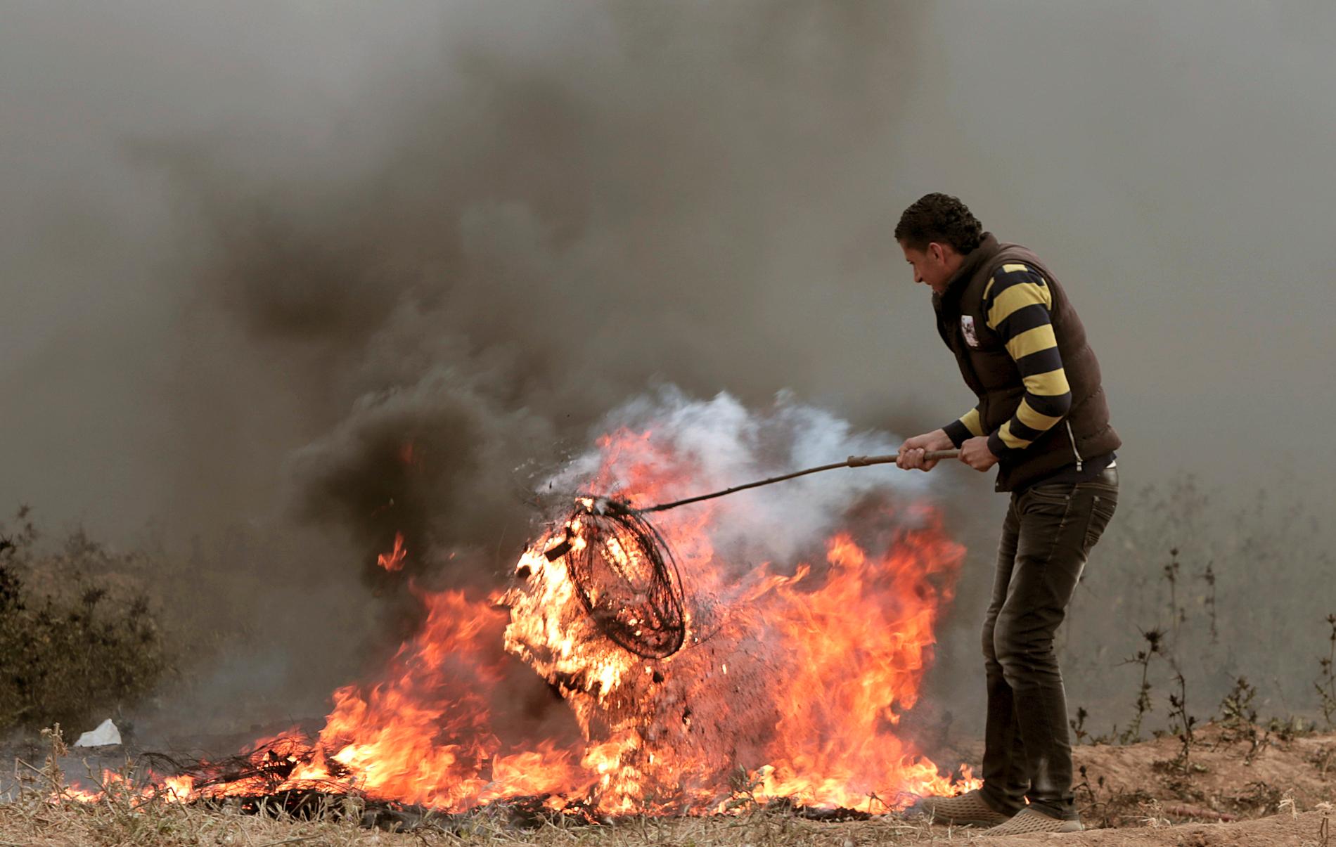 En palestinsk demonstrant bränner däck nära Gazas gräns mot Israel. Arkivbild.