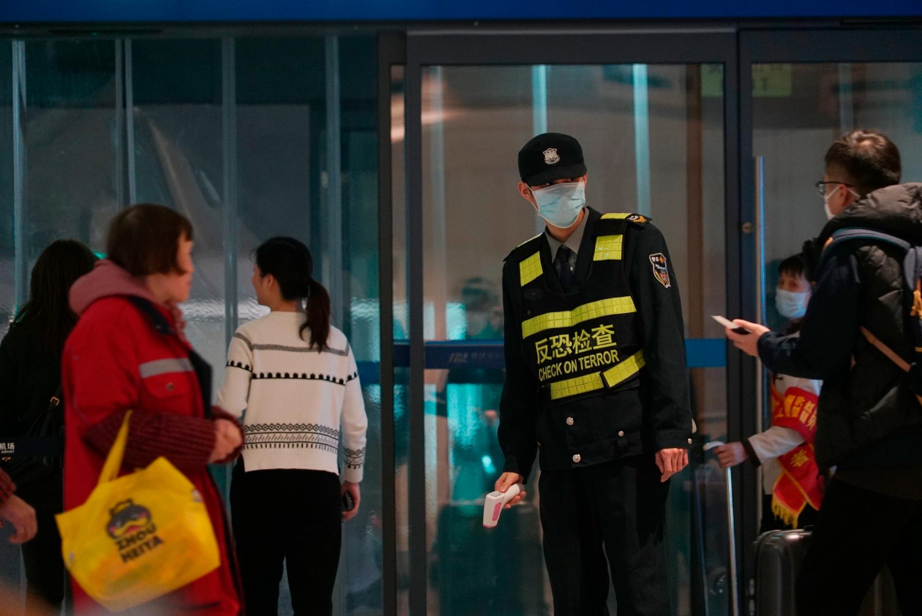 Flygplatspersonal med en ”IR-termometer” redo att testa personer som lämnar Wuhan. 