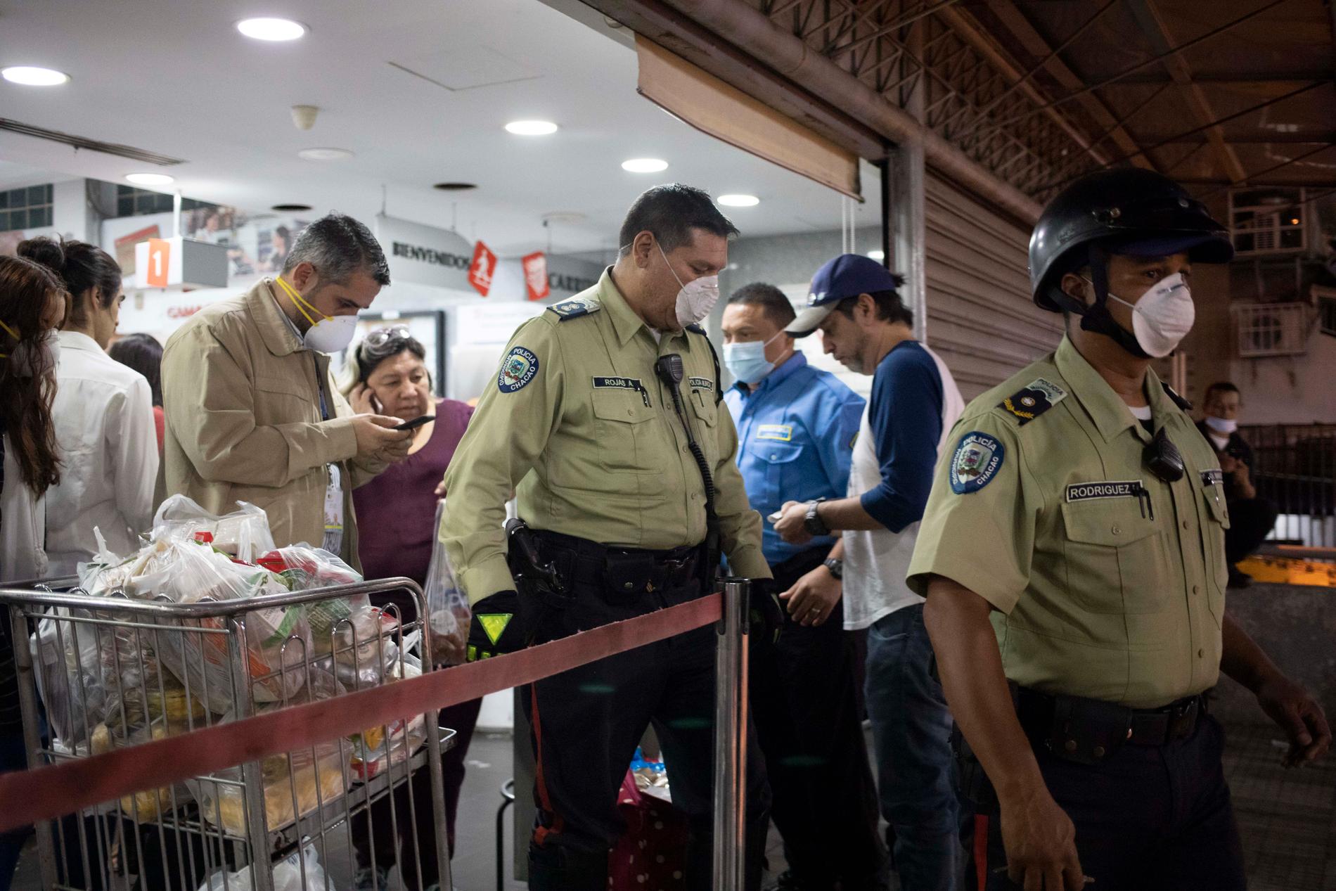 Polis lämnar en mataffär i Venezuelas huvudstad Caracas. Detta efter att ha beordrat att butiken ska stänga eftersom personer utan munskydd befann sig i den.