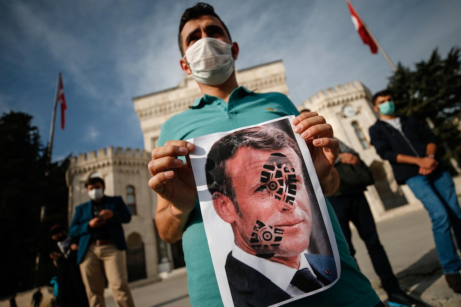 En demonstrant i Istanbul i Turkiet håller upp en bild på Frankrikes president Emmanuel Macron med en fotoavtryck över ansiktet. Vreden är stor efter Macrons kritiska uttalanden om islam.
