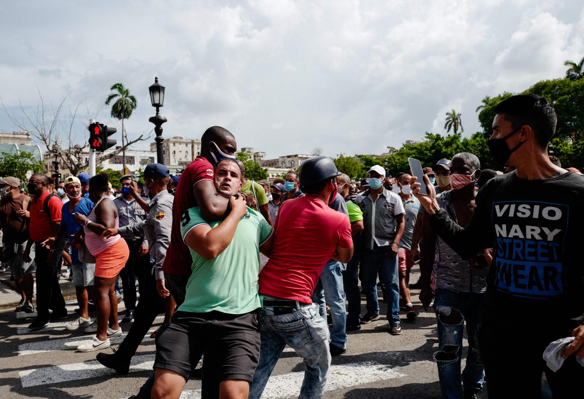 En regeringssupporter kopplar strypgrepp på en demonstrant under protester i kubanska staden San Antonio de los Baños.