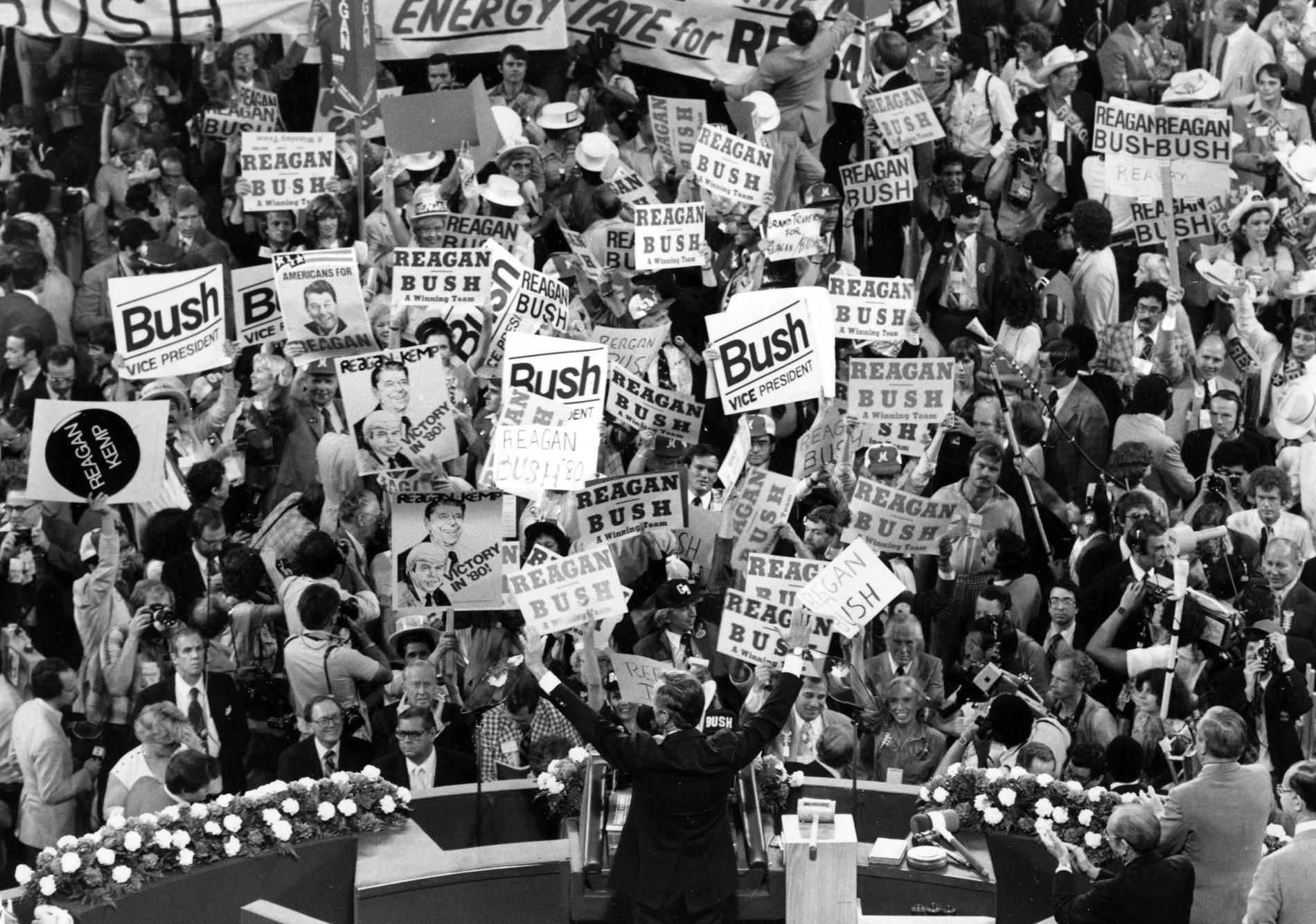 In this July 16, 1980 file photo George H.W. Bush, center foreground, acknowledges the crowd before speaking to the Republican Convention delegates in Detroit, Mich.