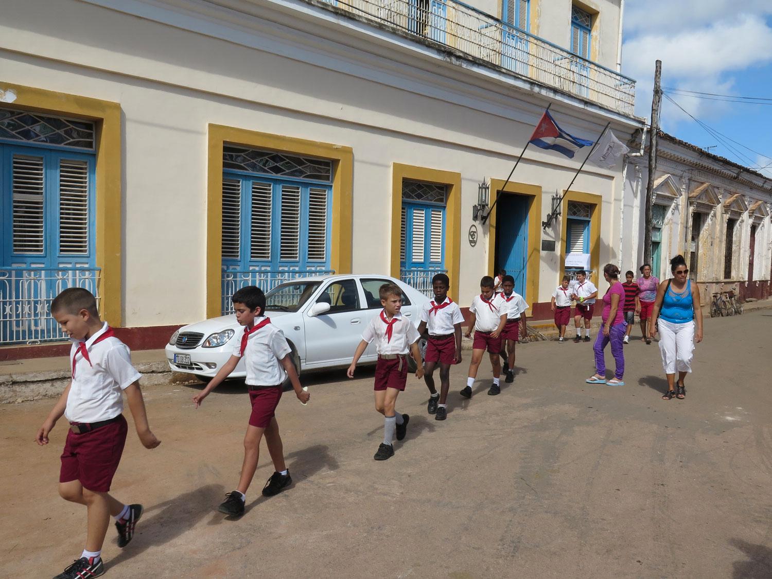 Bilen osäkert parkerad vid hotell Mascotte i Remedios. En skolklass passerar diciplinerat förbi.