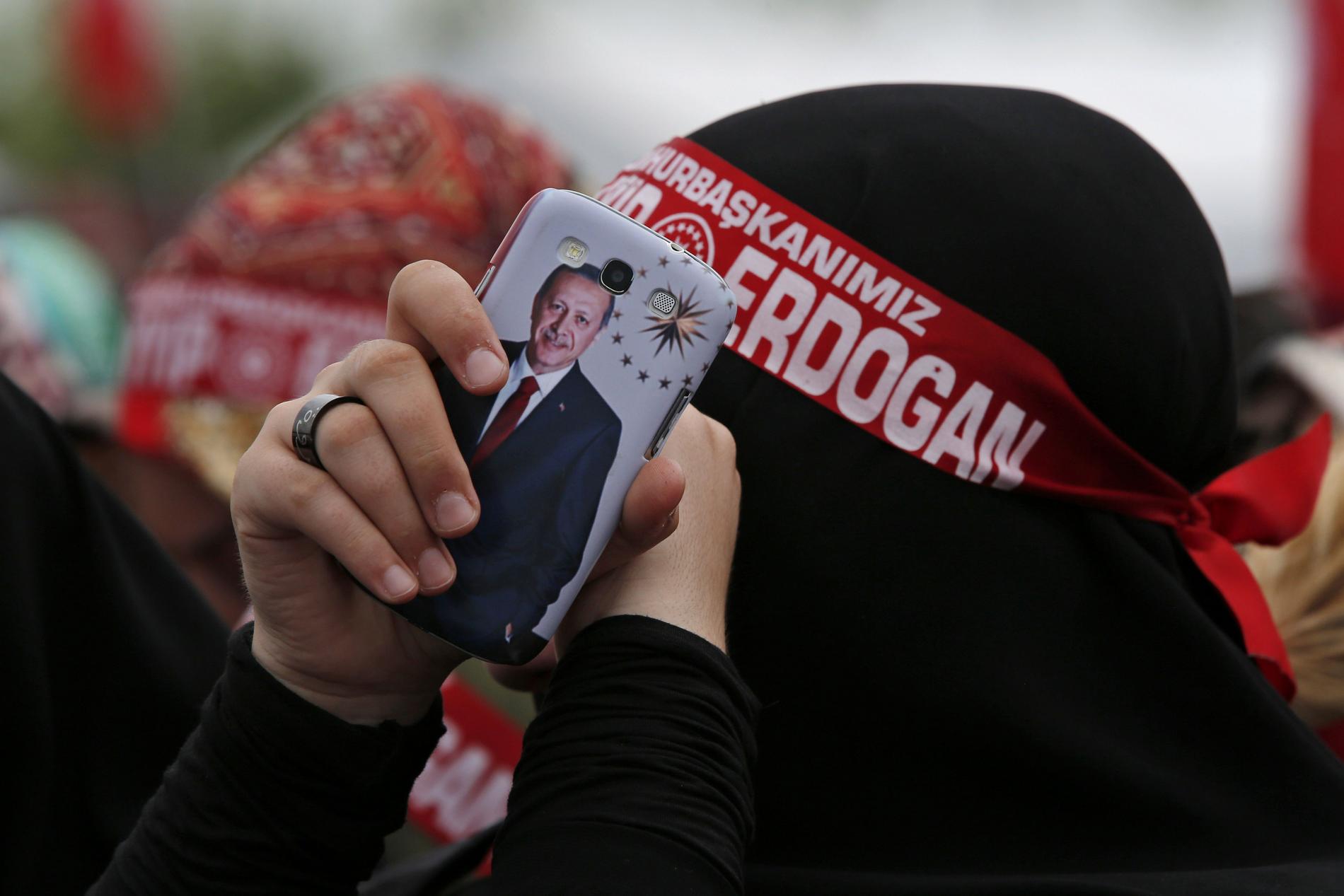En anhängare till Turkiets president Recep Tayyip Erdogan håller i en mobiltelefon, på mobilskalet är presidenten är avbildad. 