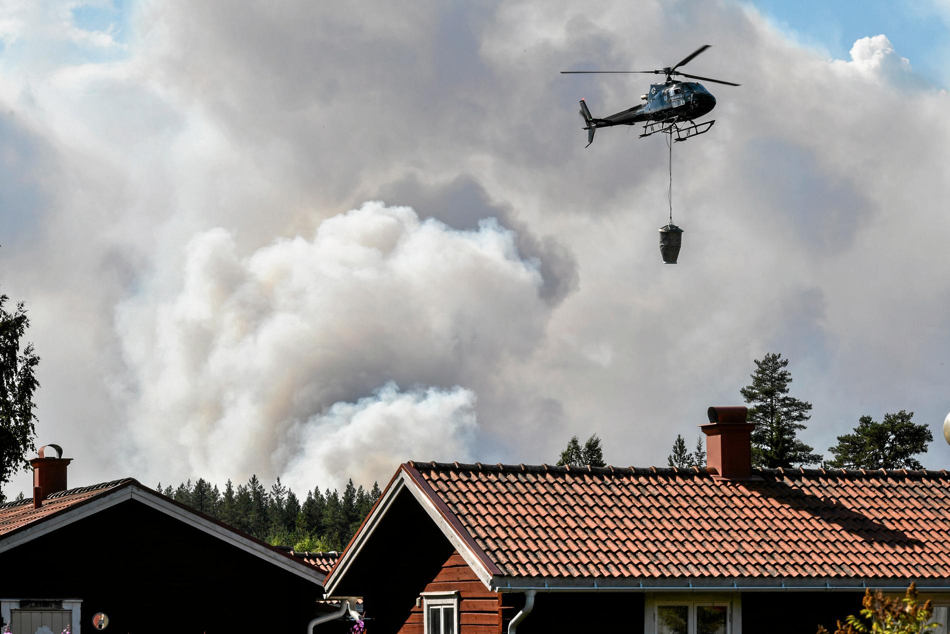En helikopter hjälper till med släckningsarbetet vid en skogsbrand nära Färila, Ljusdal.