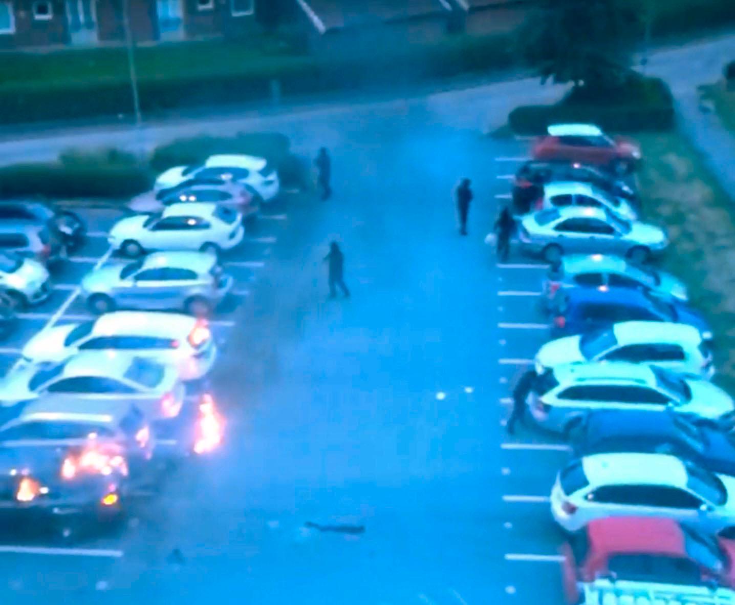 Svartklädda personer tänder eld på bilar vid Frölunda torg.