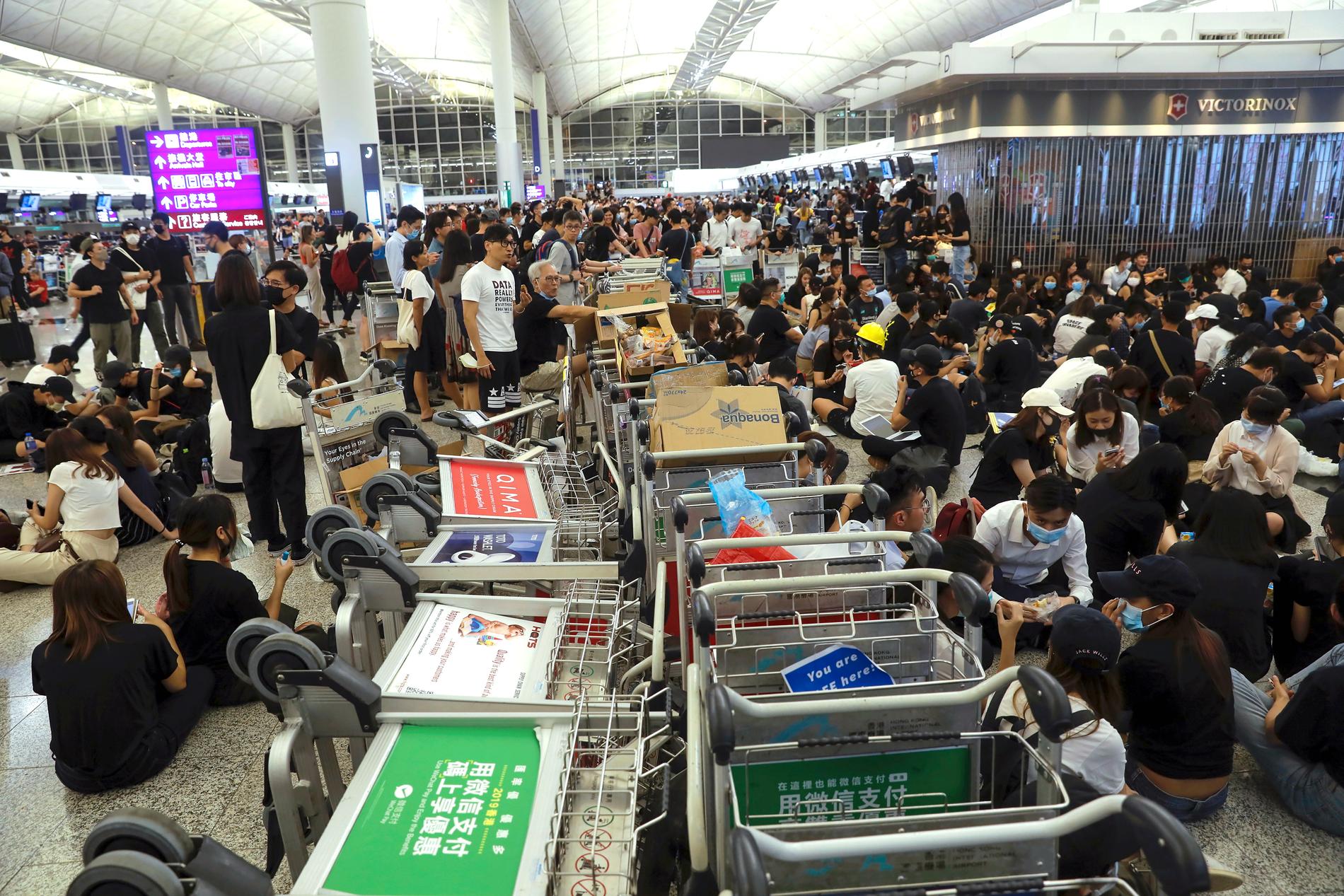 Demonstranter använder bagagevagnar för att hindra resenärer från att nå sina gater på Hongkongs flygplats.