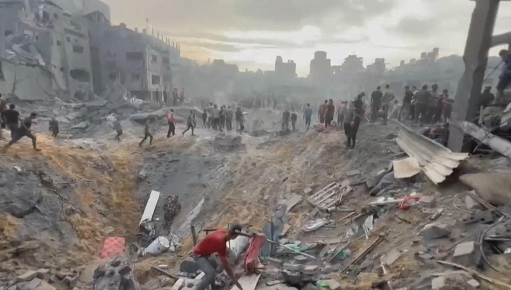 Människor gräver desperat efter överlevande under bråtet i en av de stora kratrarna efter bombattacken.